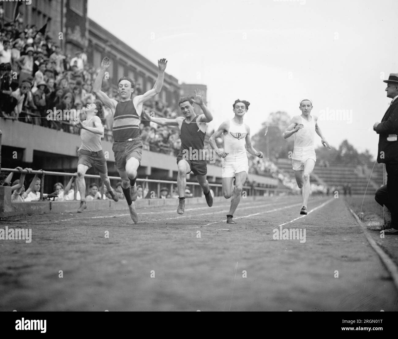 Athlètes d'athlétisme de l'école primaire participant à un relais, franchissant la ligne d'arrivée ca. 1924 Banque D'Images