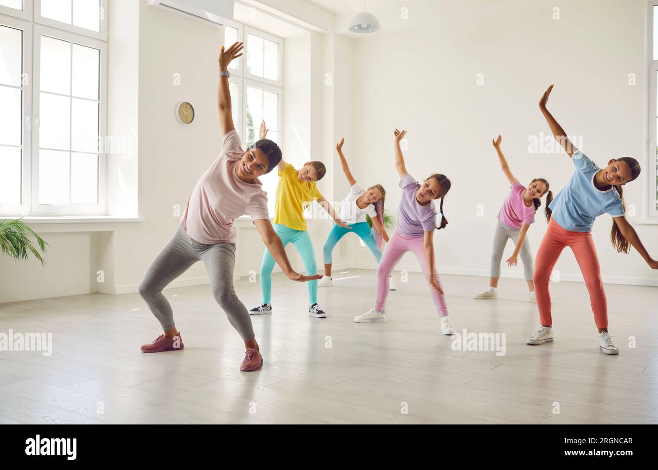 Filles souriantes formant la danse moderne se déplace ensemble en studio avec chorégraphe. Banque D'Images