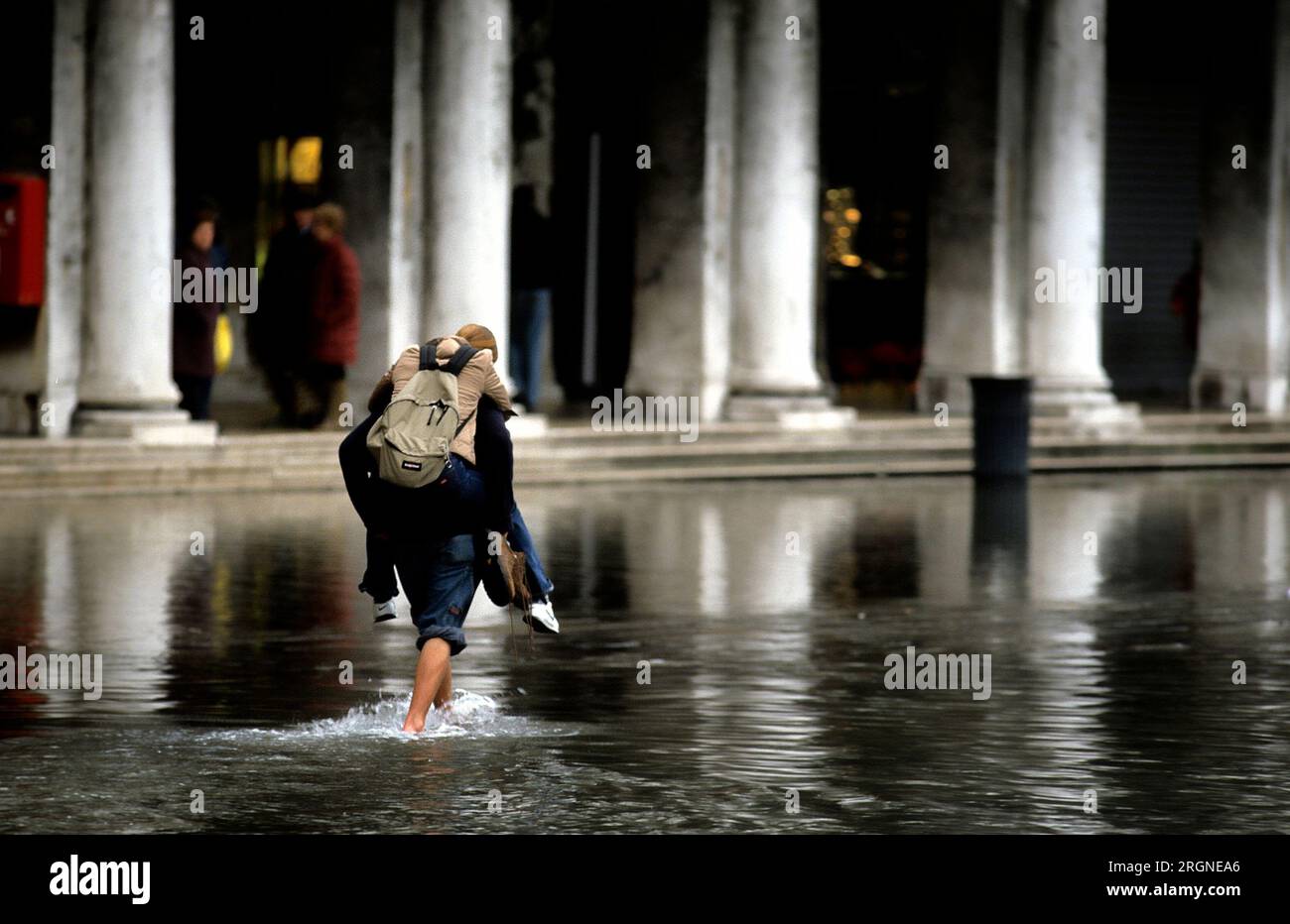 Homme cochon soutenant une femme dans les hautes eaux à San Marco, Venise Italie Banque D'Images