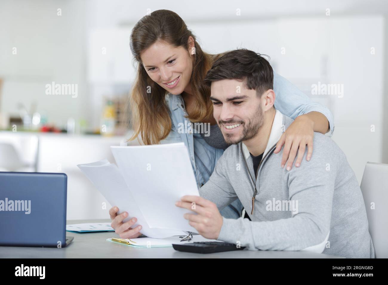 couple souriant utilisant un ordinateur portable pour s'occuper des factures de services publics Banque D'Images