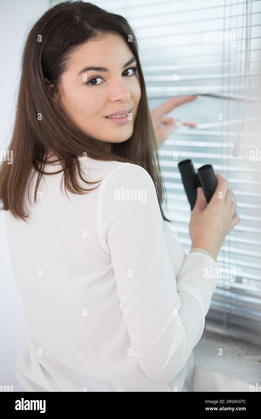 femme choquée après avoir espionné par la fenêtre avec des jumelles Banque D'Images
