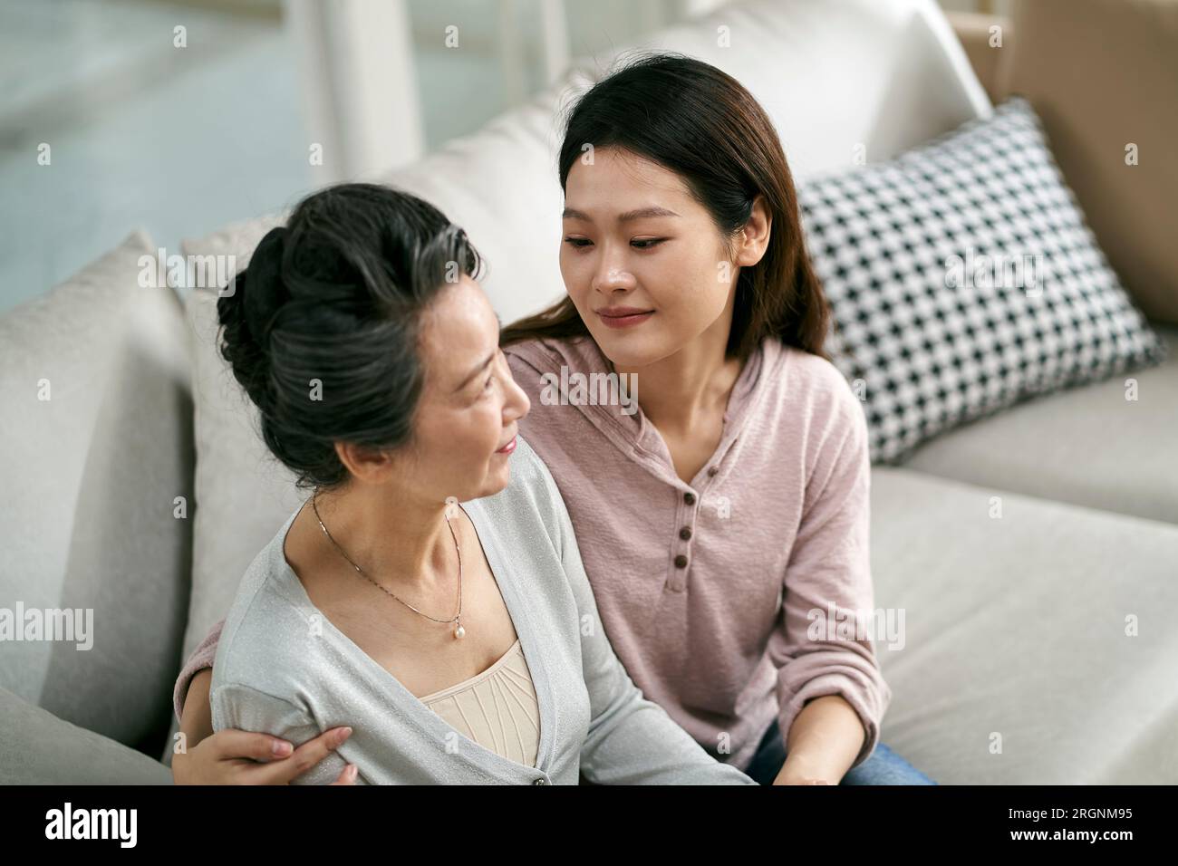 fille adulte asiatique et mère aînée assis sur le canapé à la maison ayant une conversation agréable Banque D'Images