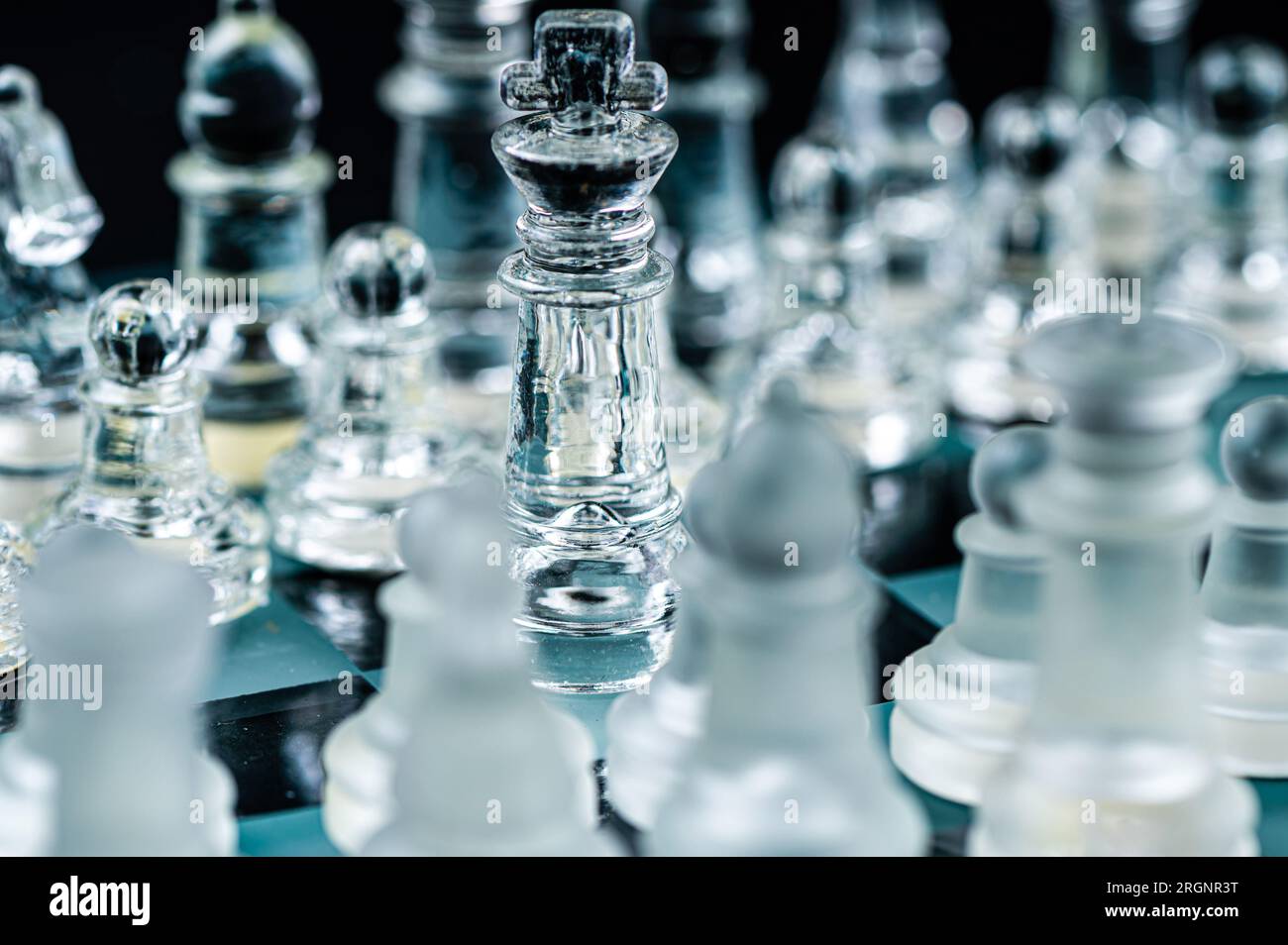 Pièces d'échecs en verre transparent sur fond sombre. Leadership, confrontation et concept de stratégie Banque D'Images