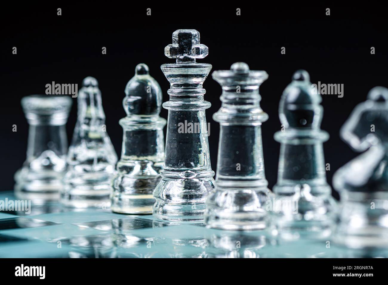 Pièces d'échecs en verre transparent sur fond sombre. Leadership, confrontation et concept de stratégie Banque D'Images