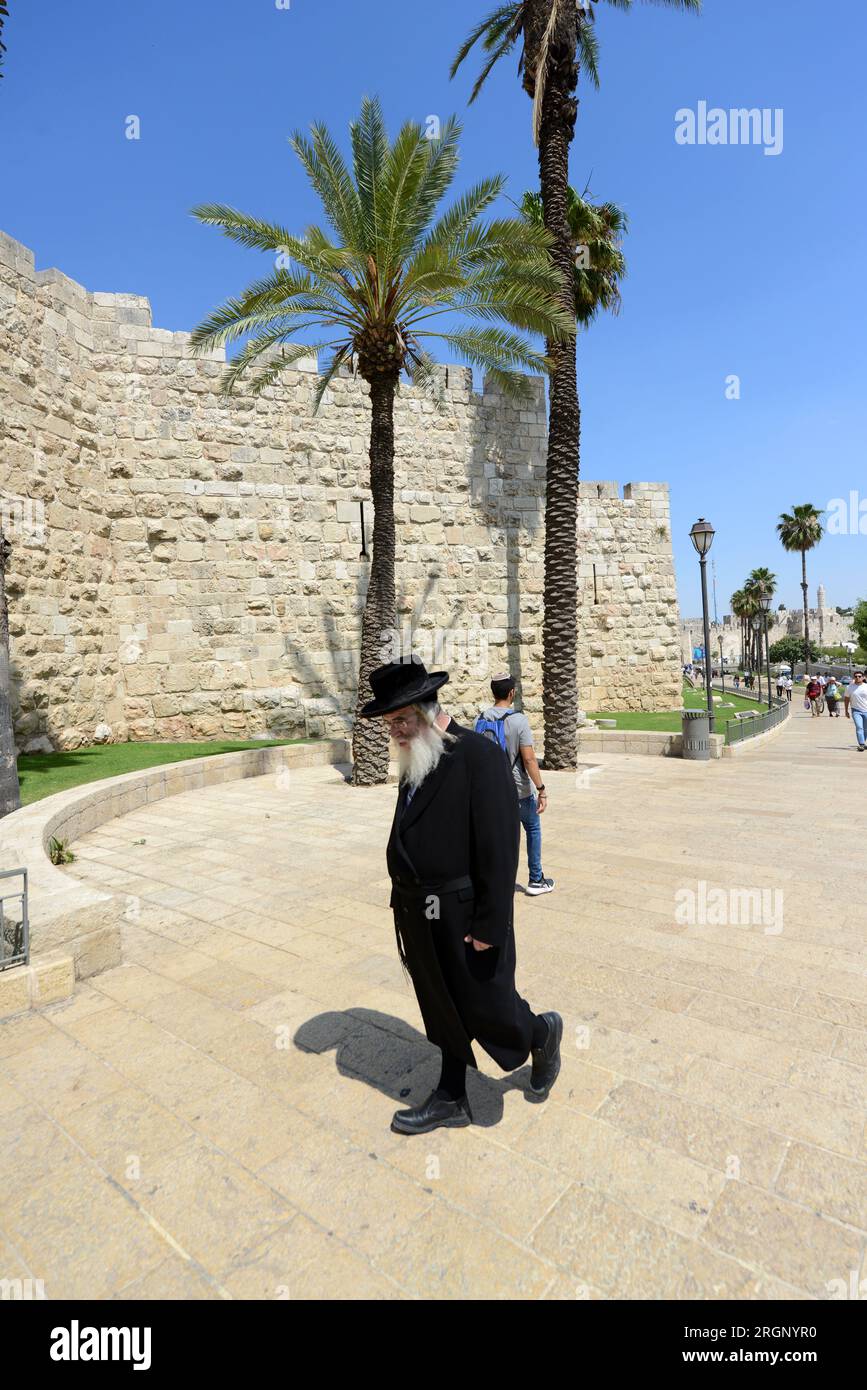 Un juif orthodoxe marchant le long des murs ottomans de la vieille ville de Jérusalem, Israël. Banque D'Images