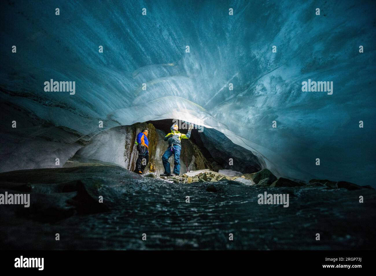 deux hommes s'émerveillent devant une rivière gelée de glace sous un glacier en fonte Banque D'Images