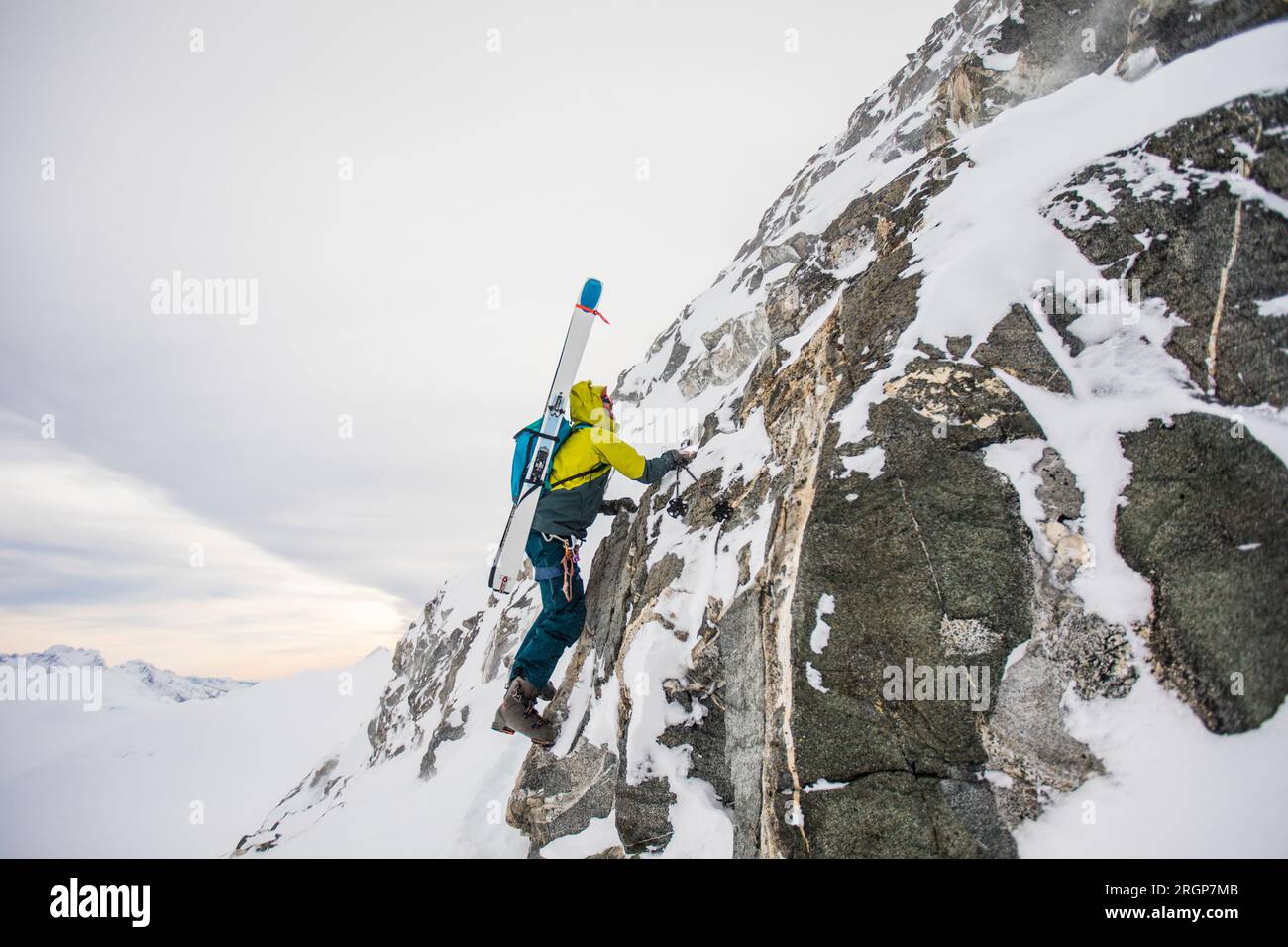 Bootpacks skieur, grimpe une falaise rocheuse abrupte vers le sommet Banque D'Images