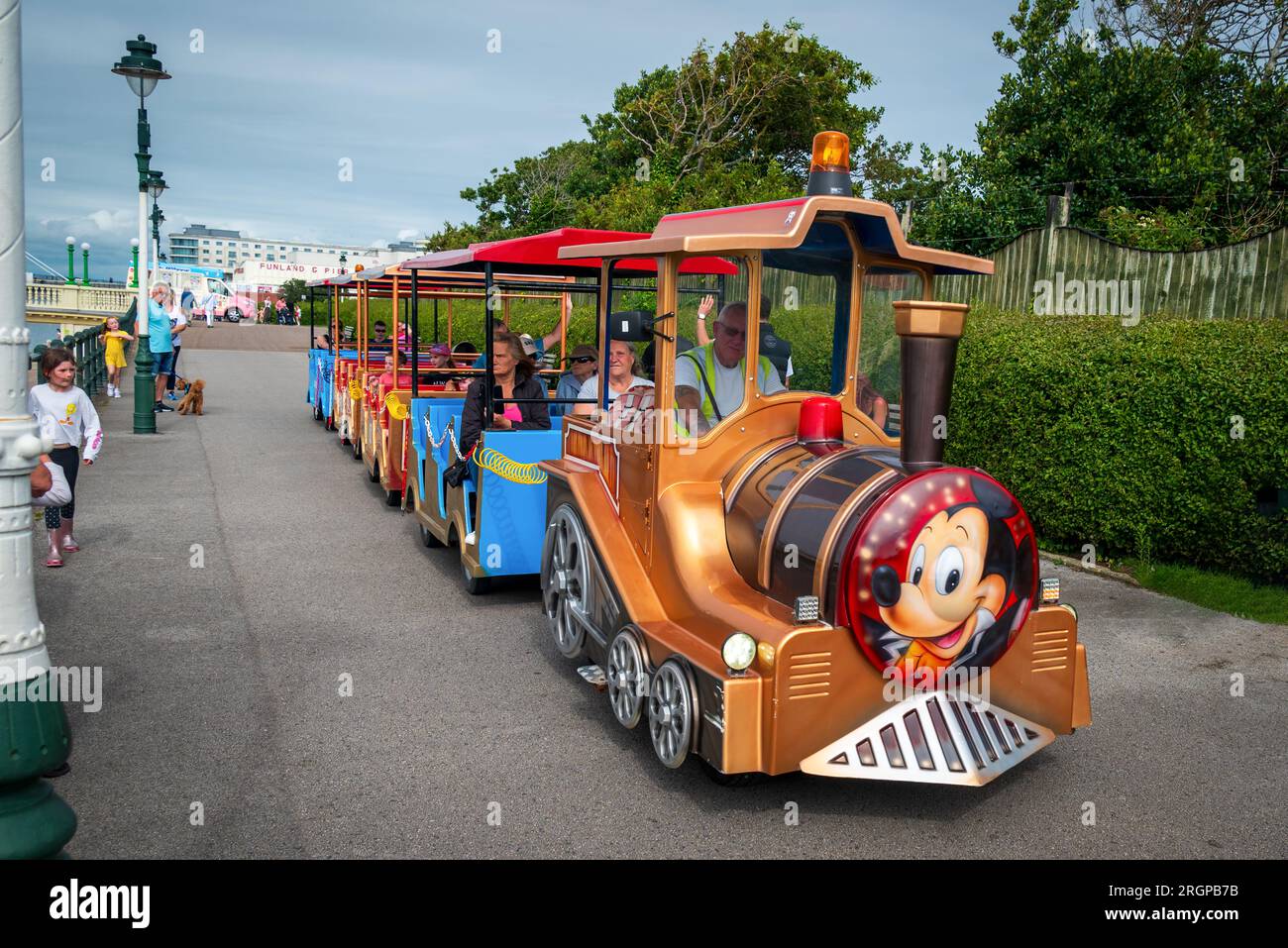 Les gens profitant du soleil par le lac Marine à Southport à cheval dans le train terrestre. Banque D'Images