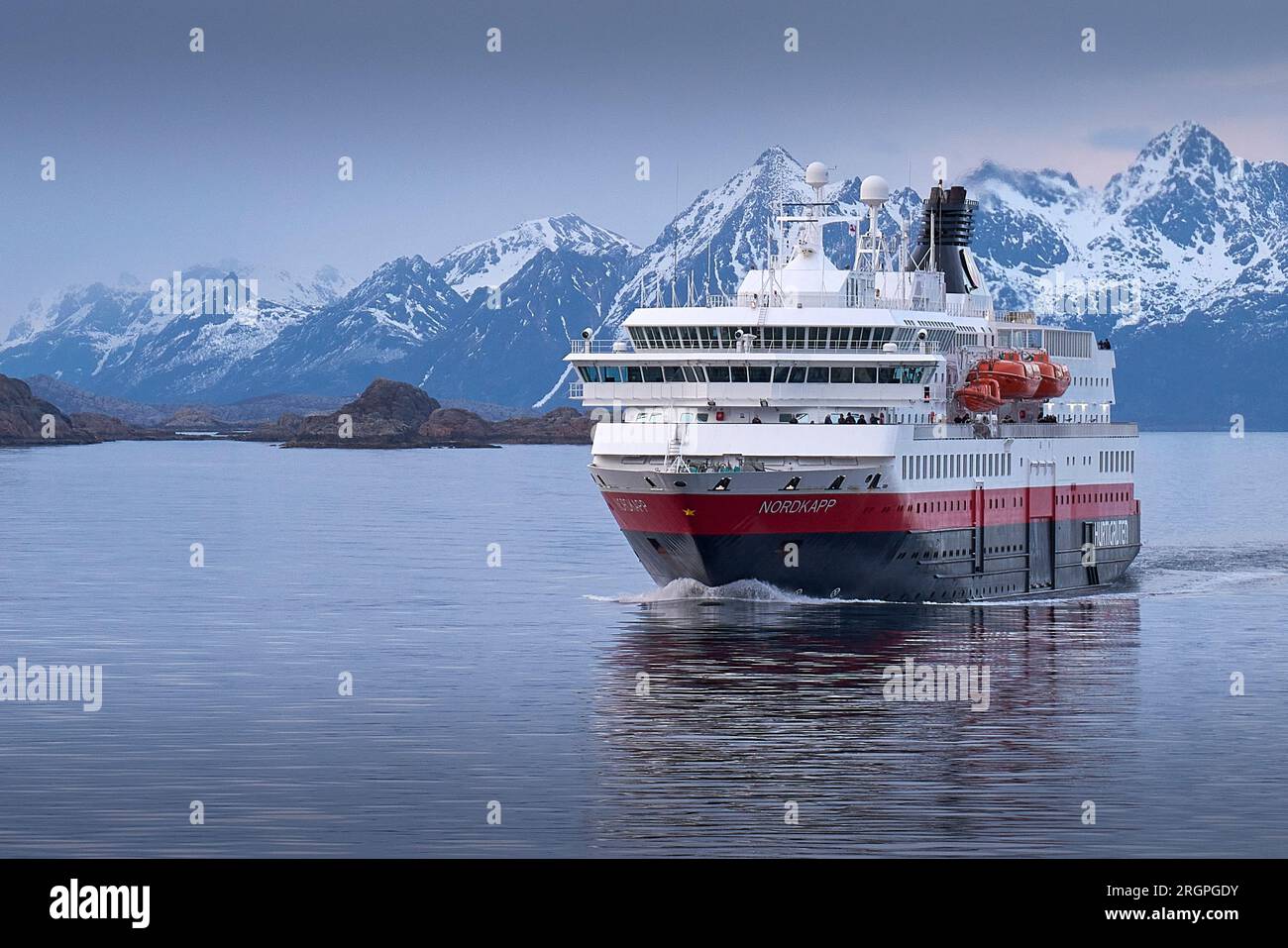 Le Norwegian Hurtigruten Ferry, MS NORDKAPP, navigue au sud de Svolvaer, les montagnes enneigées des îles Lofoten derrière. Norvège. 4 mai 2023 Banque D'Images