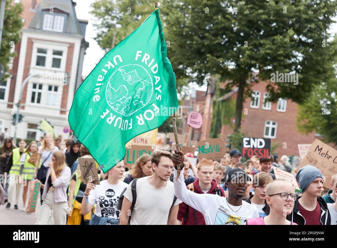 11 août 2023, Basse-Saxe, Lüneburg : un participant à une marche de protestation du mouvement climatique Fridays for future porte un drapeau avec l'inscription «Fridays for future Ukaine». La démonstration à travers Lüneburg vise, entre autres, à attirer l'attention sur la nécessité de la nouvelle ligne ferroviaire Hambourg-Hanovre. Photo : Georg Wendt/dpa Banque D'Images