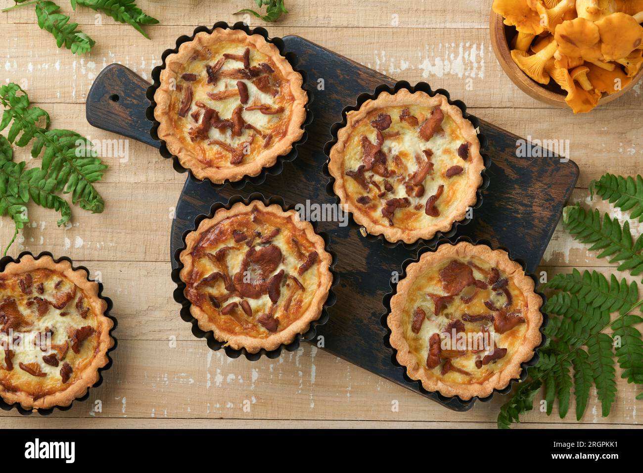 Tarte aux mains savoureuses avec des champignons chanterelles, crème et fromage sur une planche à découper sur fond de table en bois blanc rustique. Tartes maison avec saison Banque D'Images