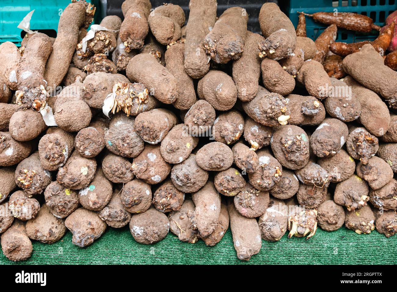 Pile de légumes d'igname, ignames exposées sur un stand de marché avec de la nourriture ethnique à Brixton, Londres, Royaume-Uni Banque D'Images