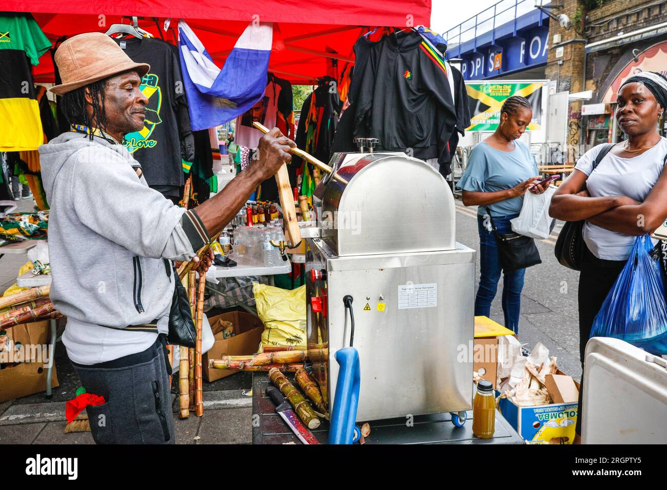 Vendeur fabriquant du jus de canne à sucre frais, Brixton Station Road Market, Brixton, South London, Angleterre Banque D'Images