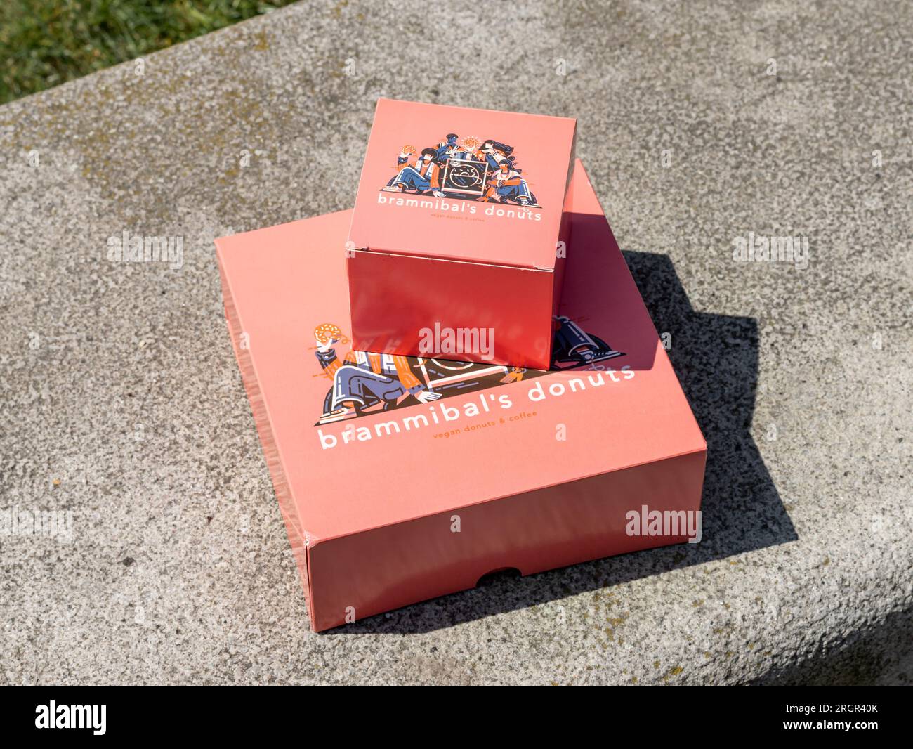 Les boîtes de Donuts de Brammibal sur un banc de pierre. Emballage fermé du beignet café végétalien et boulangerie après avoir acheté des collations sucrées. Banque D'Images