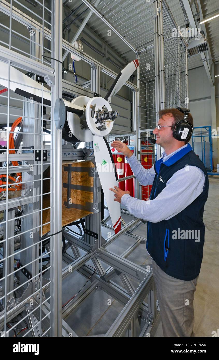 11 août 2023, Brandenburg, Strausberg : Alexander Behrens, ingénieur de développement chez APUS GmbH, se tient devant un moteur d'avion à hydrogène qu'il a développé. APUS GmbH, leader dans le développement et la fabrication d’avions à hydrogène, a ouvert le même jour une usine d’essais et d’assemblage final à Strausberg. L'installation représente un investissement important pour l'avenir de l'aviation et aidera APUS à développer et à tester ses avions fonctionnant à l'hydrogène. Le centre d'essai du complexe est principalement utilisé pour les essais de propulsion. À cette fin, un banc d'essai a été construit pour tester la pile à combustible, les batteries et l'hybride Banque D'Images