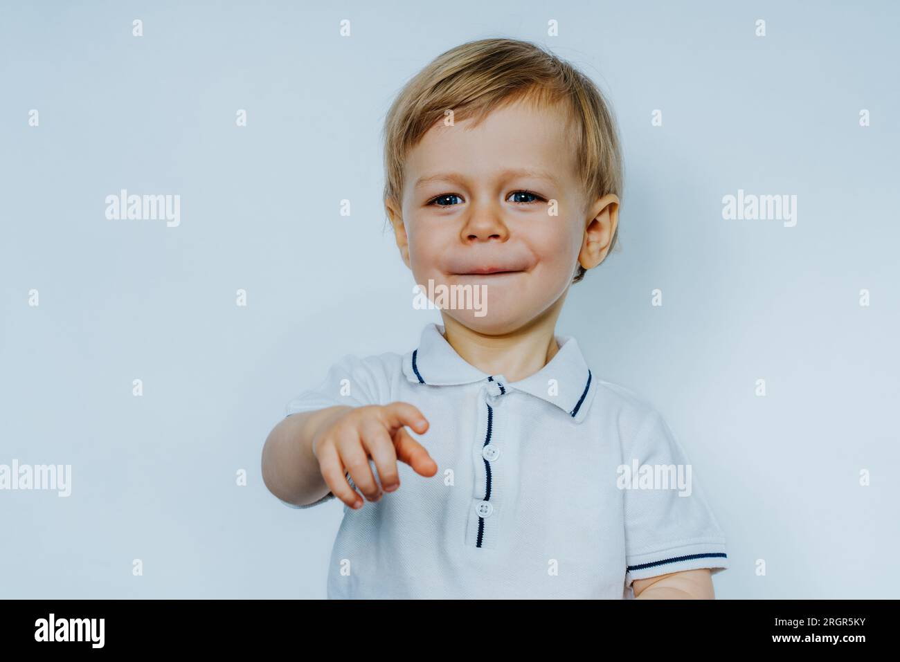 Enfant souriant de deux ans pointant vers l'avant Banque D'Images