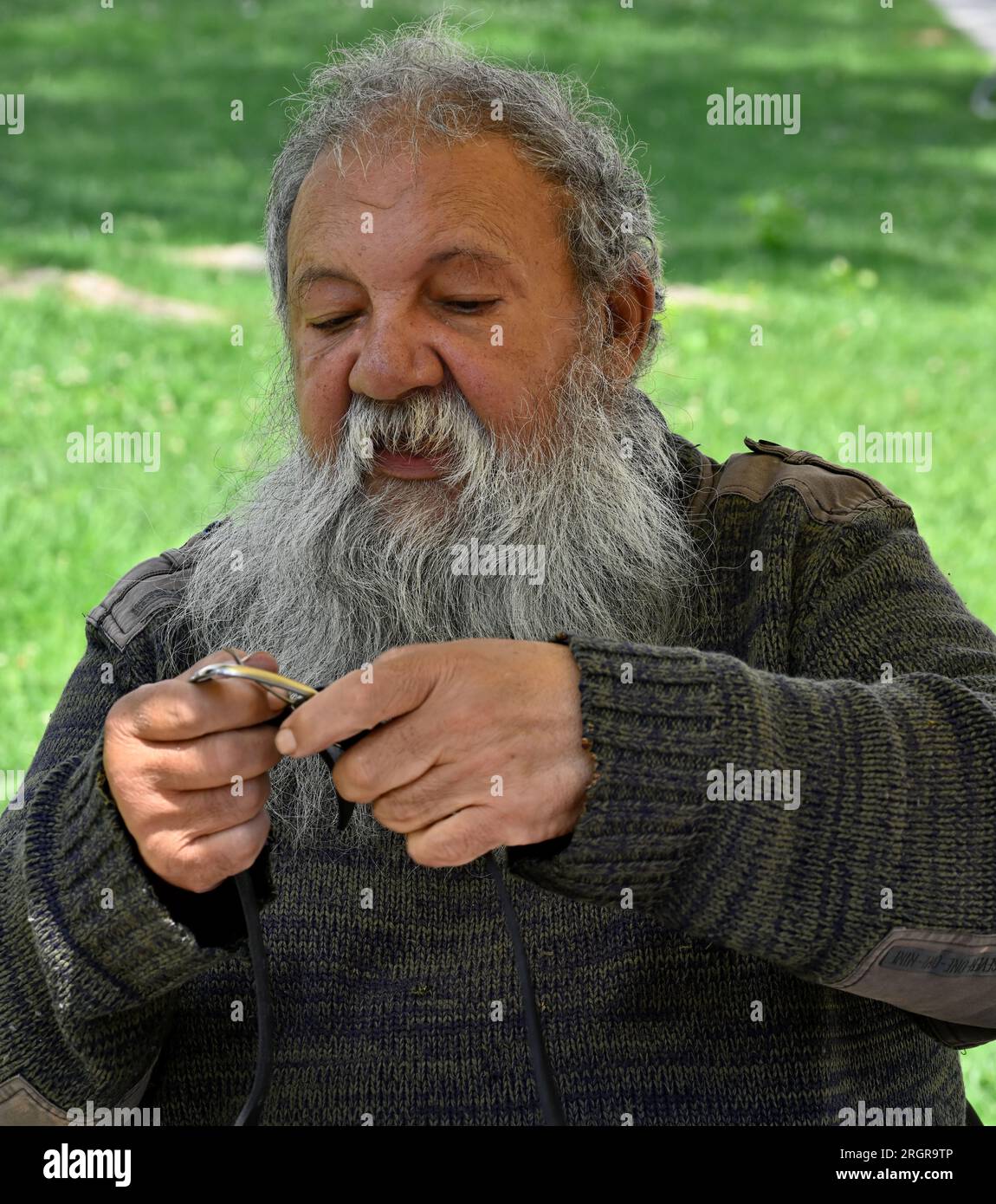 Portrait d'un homme portugais plus âgé avec la barbe grise regardant l'objet qu'il tient dans ses mains Banque D'Images