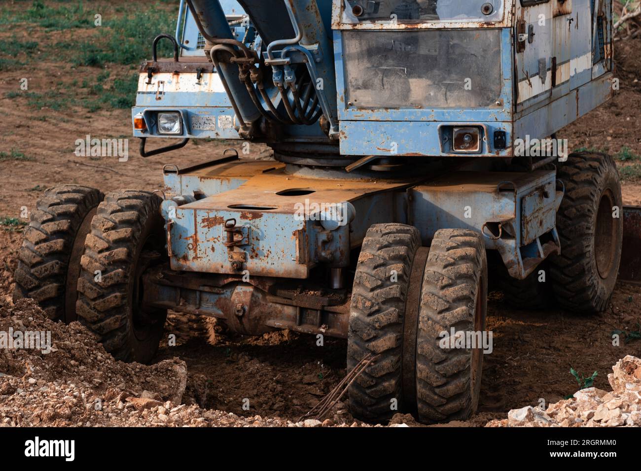 Une vieille pelle bleue rouillée se trouve sur un chantier de construction. Le godet rouillé d'une vieille pelle est abaissé au sol. Banque D'Images