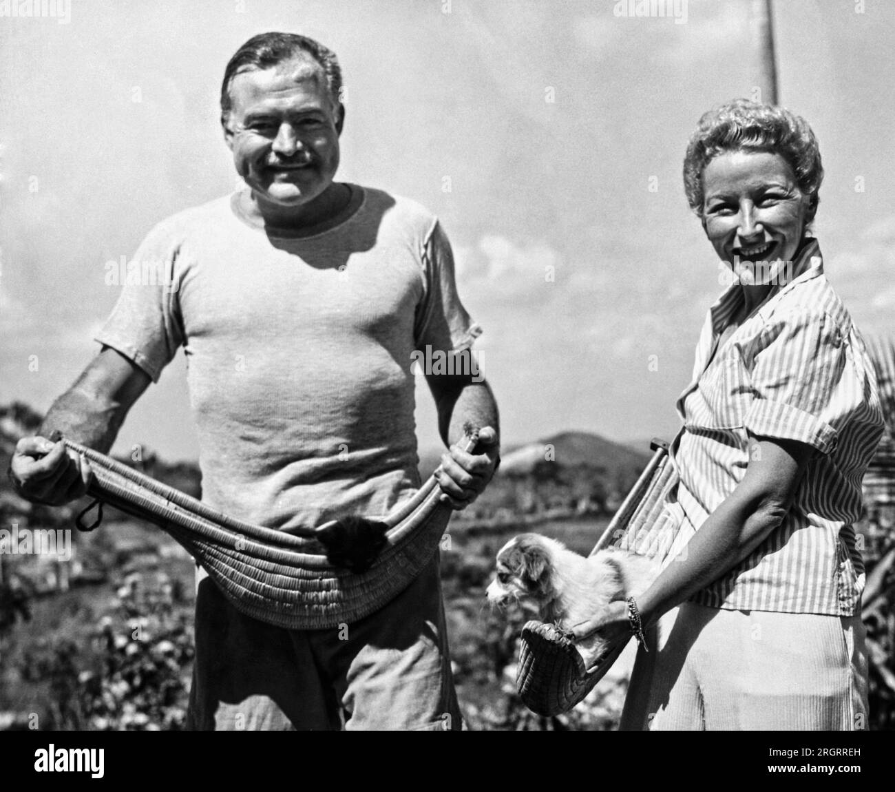 La Havane, Cuba : 20 mars 1946 auteur Ernest Hemingway et sa quatrième épouse, Mary Welsh, tiennent leurs animaux de compagnie dans des paniers jai alai sur la ferme Hemingway à San Francisco de Paulo, une banlieue de la Havane. Banque D'Images