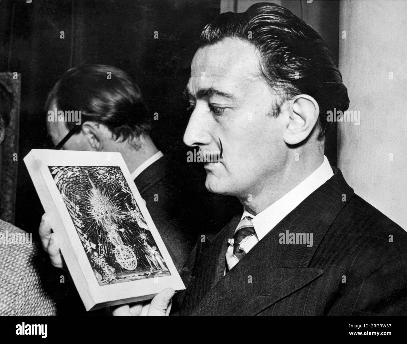 Londres, Angleterre : 3 décembre 1951 l'artiste surréaliiste Salvador Dali tient un croquis miniature d'une peinture, 'l'Assomption de la Vierge' lors d'une exposition de son travail à la Broton Street Lefevre Gallery. Il commencera bientôt à travailler sur la peinture en taille réelle. Banque D'Images