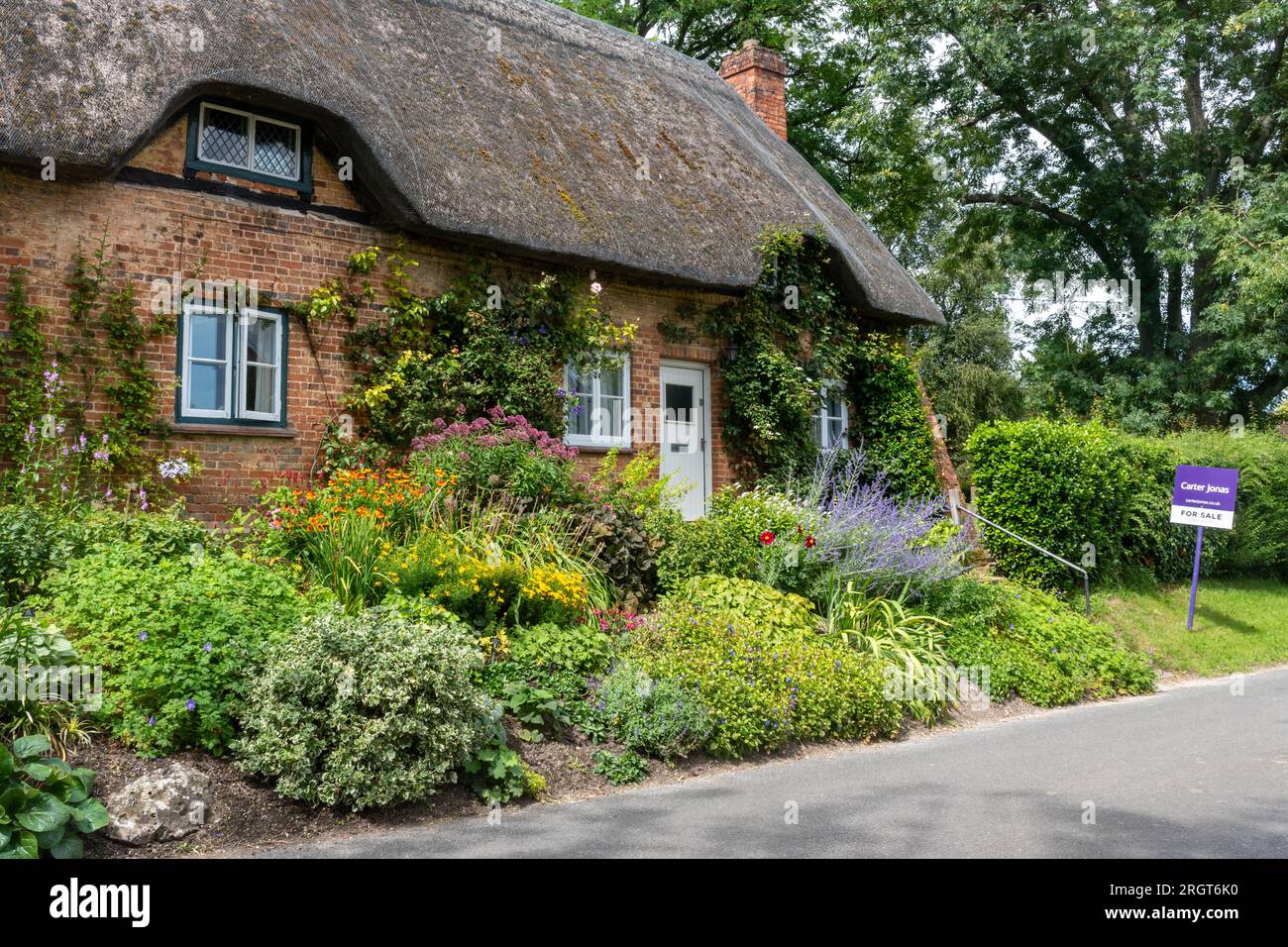 Joli chalet de chaume et jardin de fleurs dans le village de Longstock, Hampshire, Angleterre, Royaume-Uni, avec des agents immobiliers à vendre conseil. Marché immobilier Banque D'Images