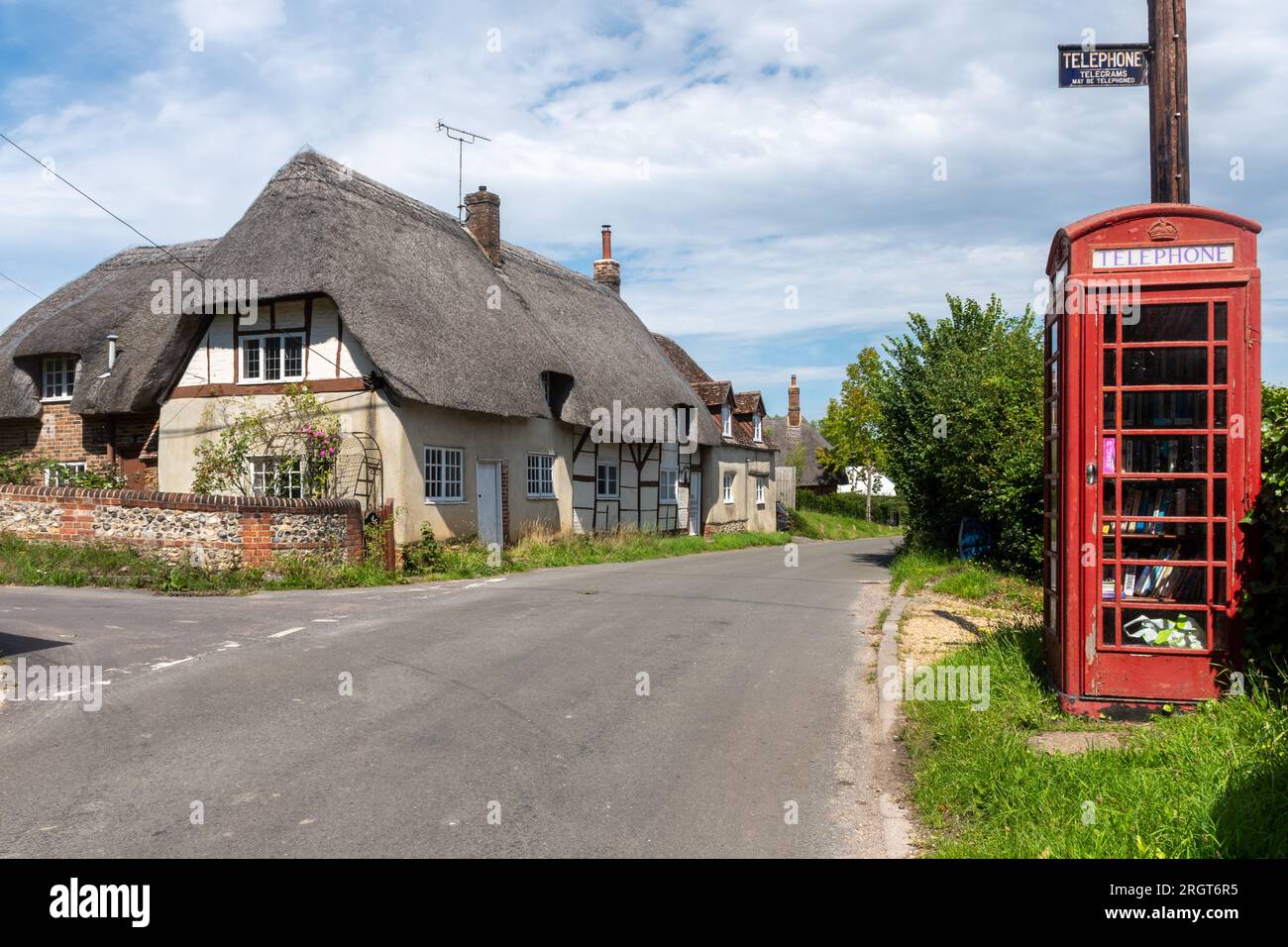 Boîte téléphonique rouge dans le village de Longstock avec la lecture historique de vieux signes télégrammes téléphoniques peuvent être téléphonés, Hampshire, Angleterre, Royaume-Uni Banque D'Images