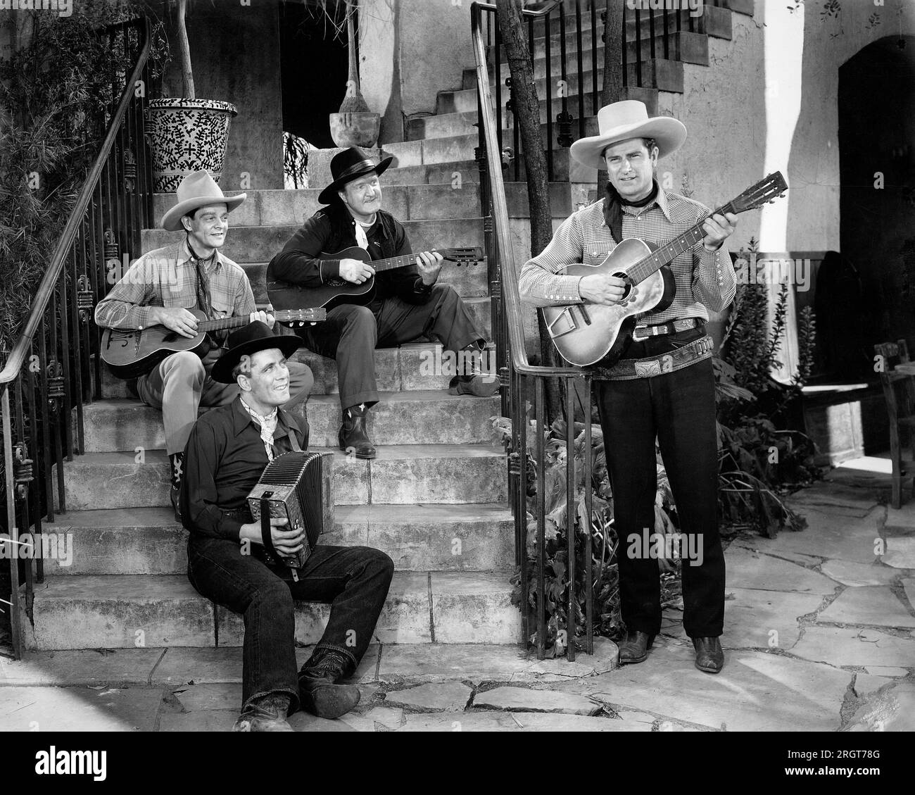 Ray Whitley (debout, guitare acoustique) et les six Bar Cowboys, sur le plateau du film, 'Renegades du Rio Grande', Universal Pictures, 1945 Banque D'Images