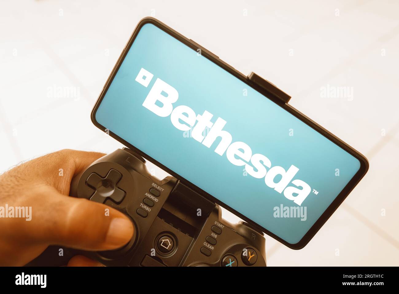 Sur cette photo, une personne joue sur un joystick et le logo Bethesda Softworks s'affiche sur l'écran d'un smartphone. Banque D'Images Sur cette photo, une personne joue sur un joystick et le logo Bethesda Softworks s'affiche sur l'écran d'un smartphone. Banque D'Images