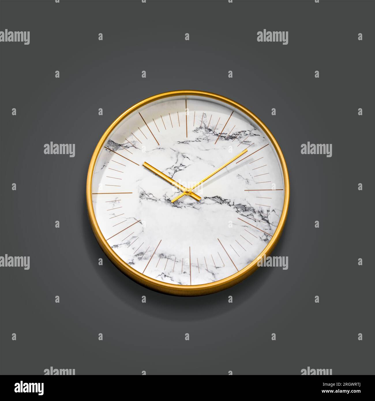 Horloge dorée sur mur gris foncé avec ombre et espace de copie Banque D'Images