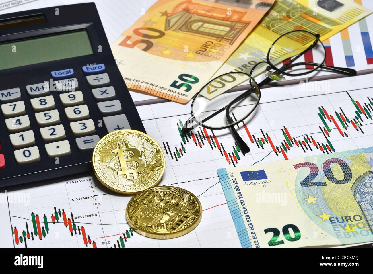 Calculatrice, bitcoin phisique, monnaie euro avec des graphiques et des  lunettes au bureau. Concept commercial Photo Stock - Alamy