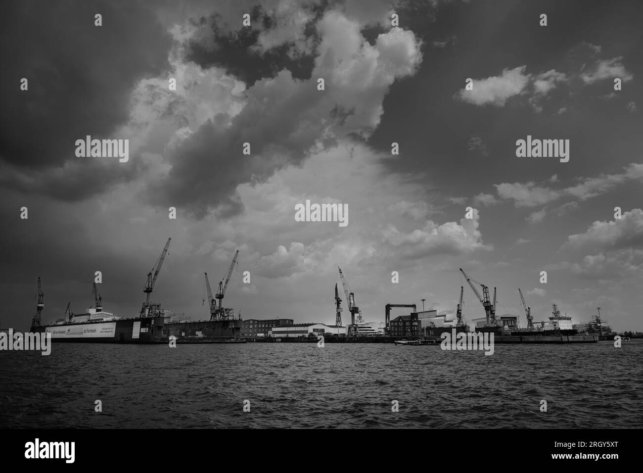 Hambourg, Allemagne - juin 17 2023 : Blohm und Voss Swimming Dock 11 sur la rivière Elbe avec des grues dans un paysage urbain noir et blanc dramatique Banque D'Images