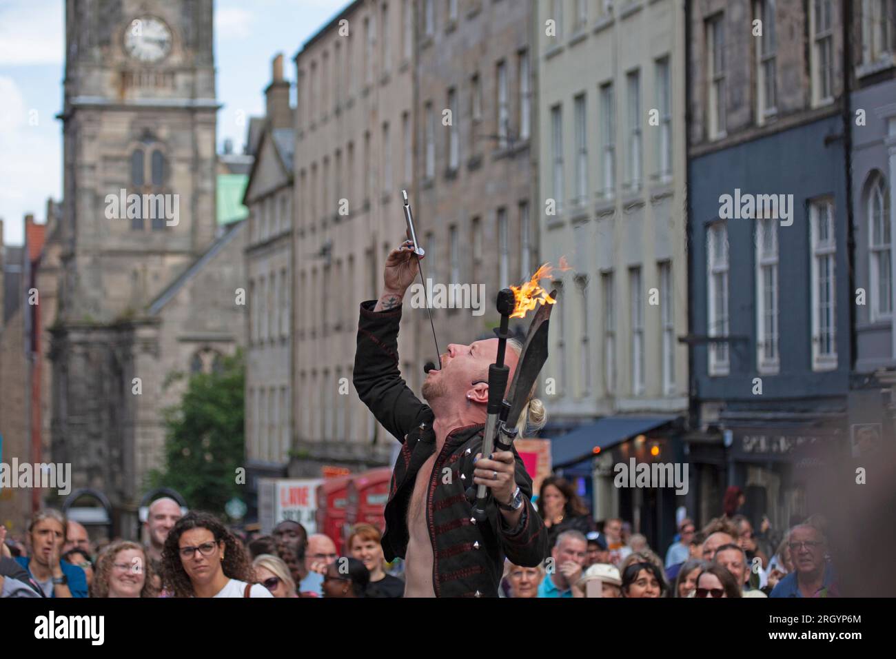 Royal Mile, Édimbourg, Écosse, Royaume-Uni. 12 août 2023. Edinburgh Festival Fringe, artistes de rue dans High Street se produisant devant un grand public, venteux pour ceux qui jonglent avec le feu et sur les plates-formes, soleil et douche lourde occasionnelle.photo : l'artiste de rue Tommy exécute son numéro d'épée sur High Street. Crédit : Archwhite/alamy Live News. Banque D'Images