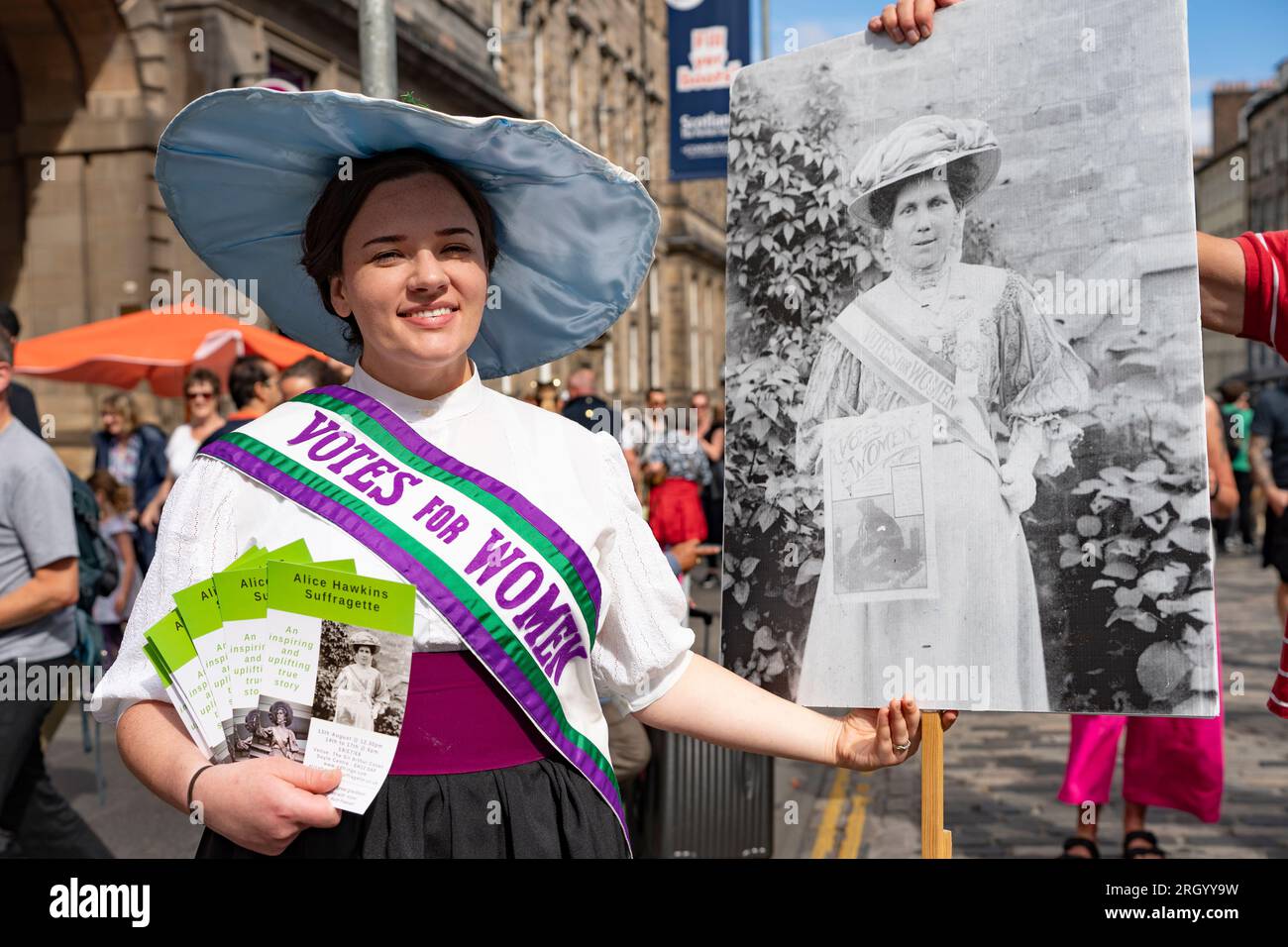 Édimbourg, Écosse, Royaume-Uni. 12 août 2023. Les températures chaudes et le soleil ont vu des milliers de visiteurs dans le centre-ville d'Édimbourg pendant les festivals International et Fringe. Le Royal Mile était extrêmement occupé alors que le public venait regarder des artistes de rue. Pic ; actrice fait la promotion de l'émission Fringe Alice Hawkins. Suffragette sur le Royal Mile. Iain Masterton/Alamy Live News Banque D'Images