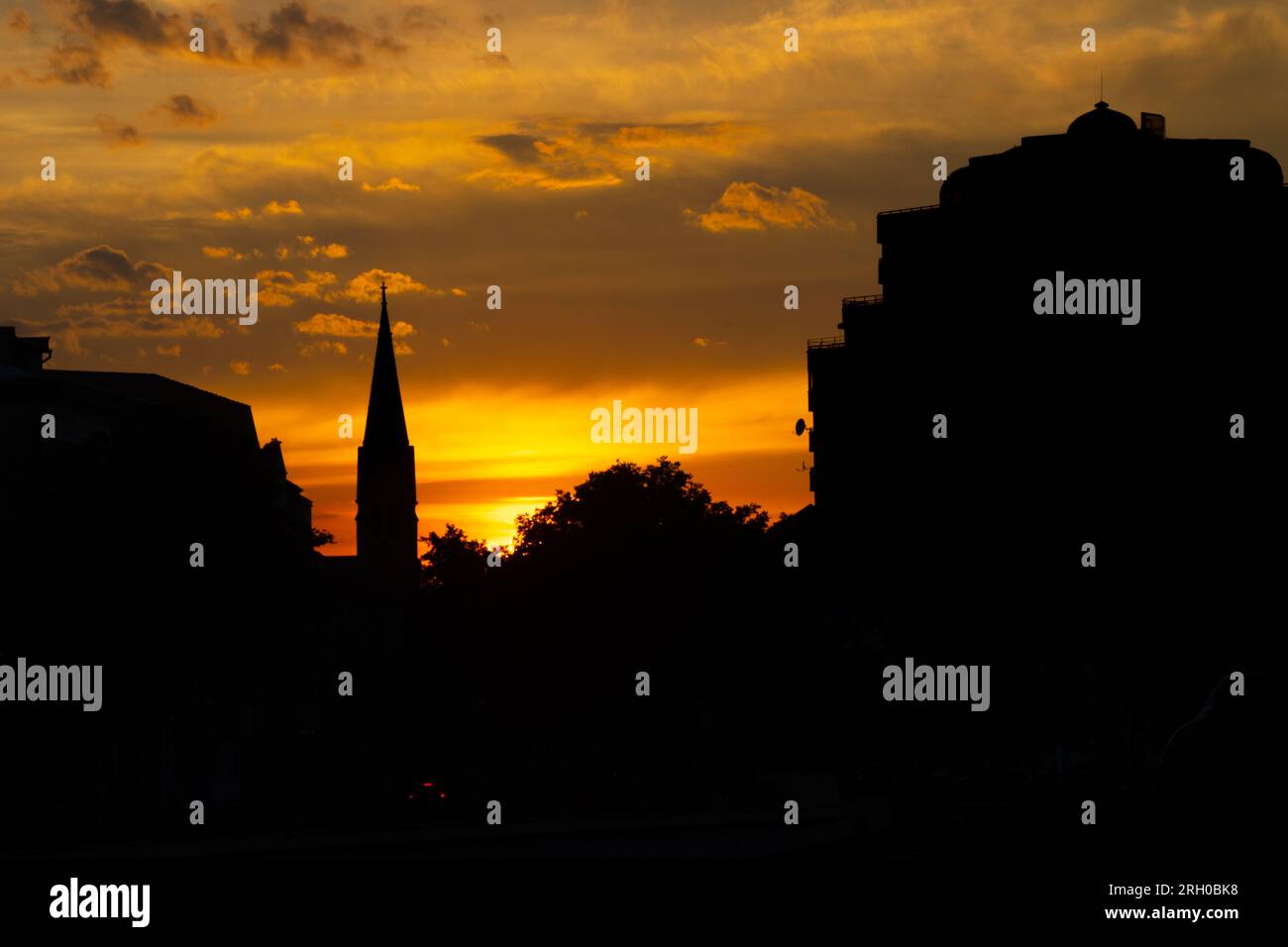 Silhouettes de bâtiments historiques contre un ciel orange au crépuscule à Oradea, Roumanie Banque D'Images