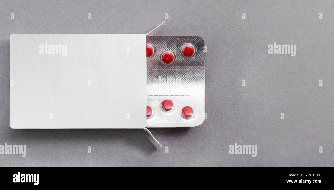 Paquet avec comprimés rouges médicaments maquette, modèle sur la table grise. Pilules antibiotiques en blister. Banque D'Images