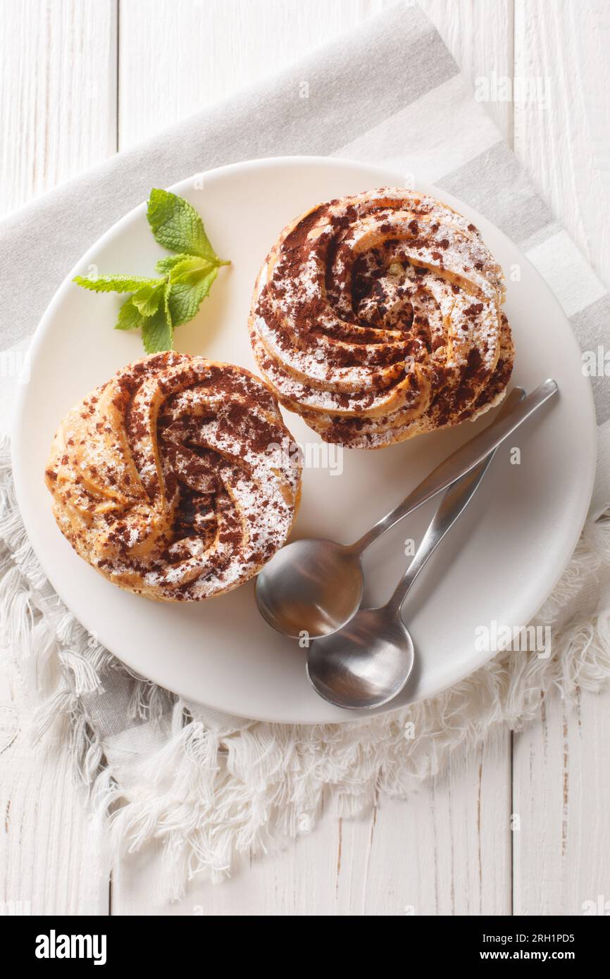 Dessert français paris-brest avec du sucre en poudre et du cacao closeup sur une assiette sur la table en bois. Vue verticale de dessus Banque D'Images