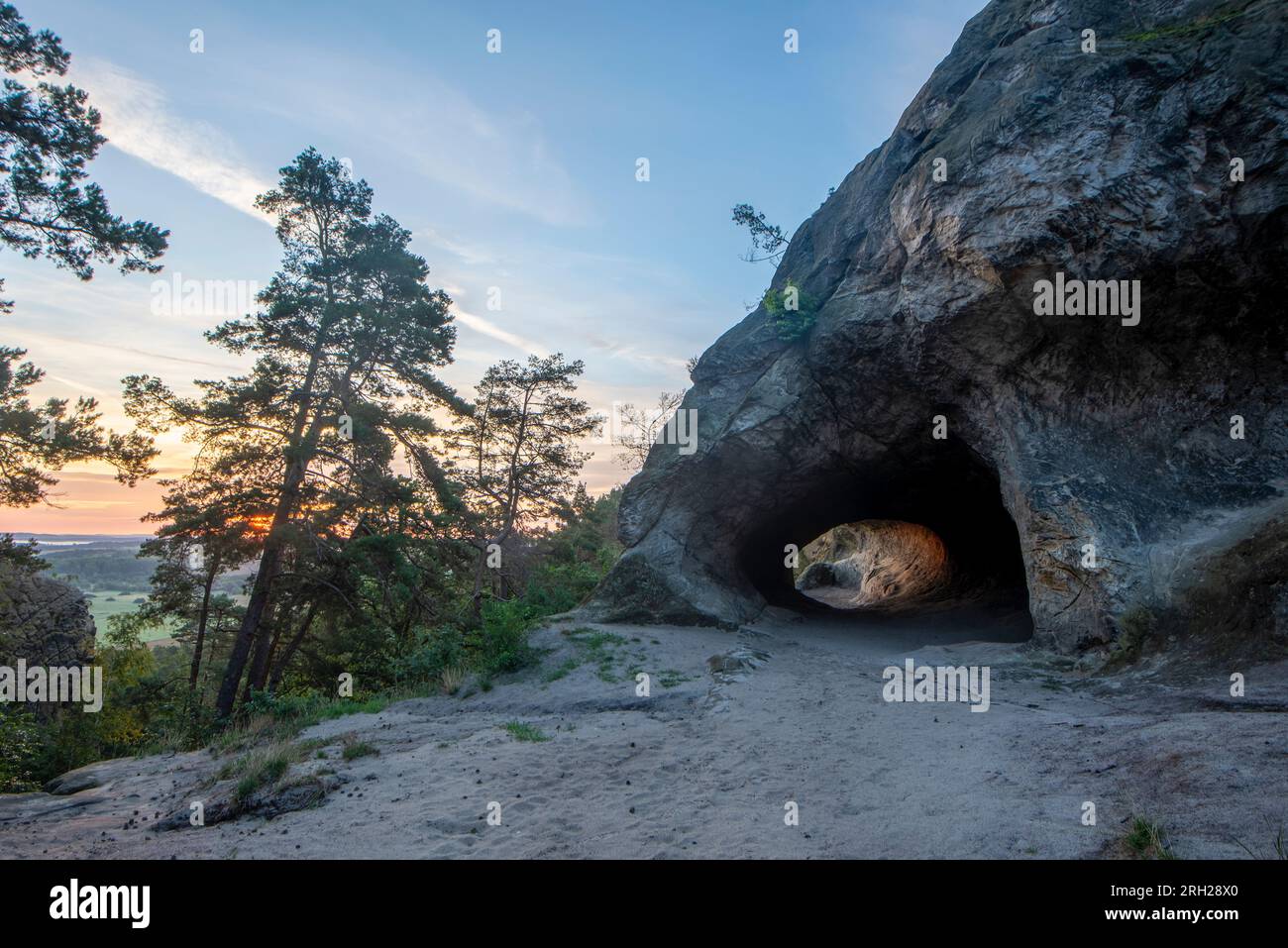 Le soleil se lève derrière une grotte aux armoiries de Hambourg. La formation de grès appartient au mur du Diable dans les montagnes du Harz. Banque D'Images