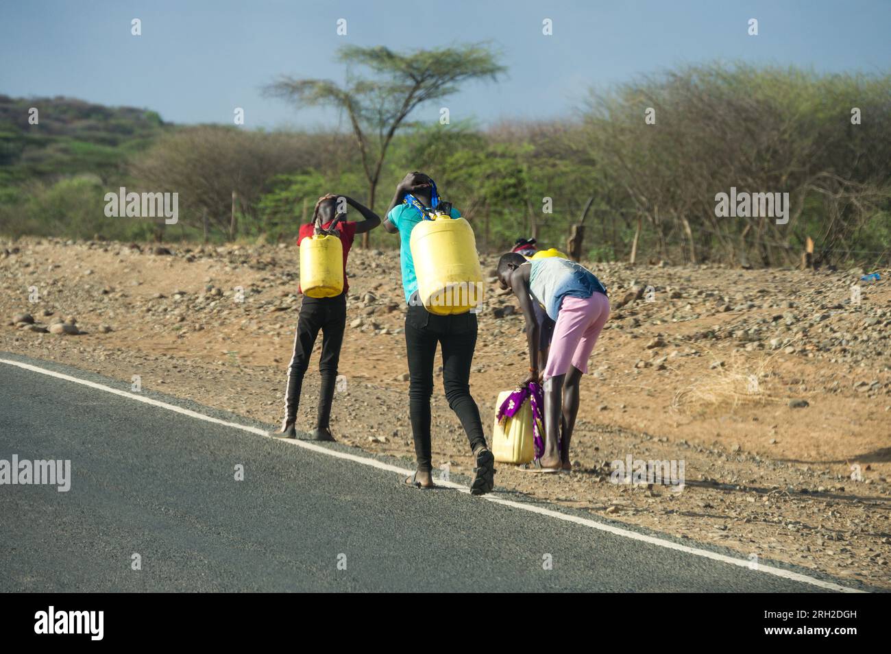 Un groupe d'enfants transportant de grands conteneurs d'eau jaunes au bord de la route, Kenya Banque D'Images