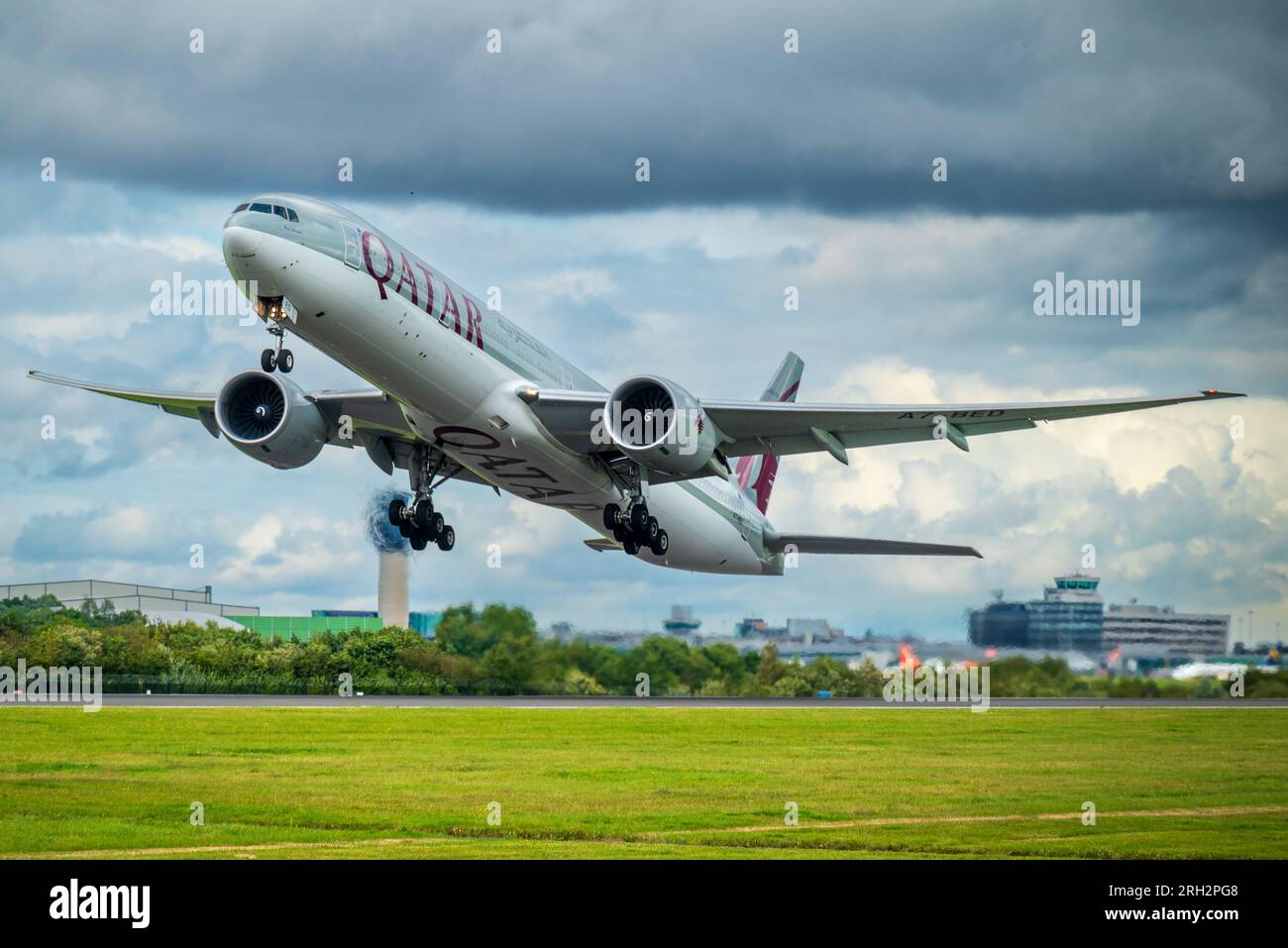 Qatar Airways Boeing 777-3DZ/ER.avec terminbal de l'aéroport de Manchester en arrière-plan. Banque D'Images