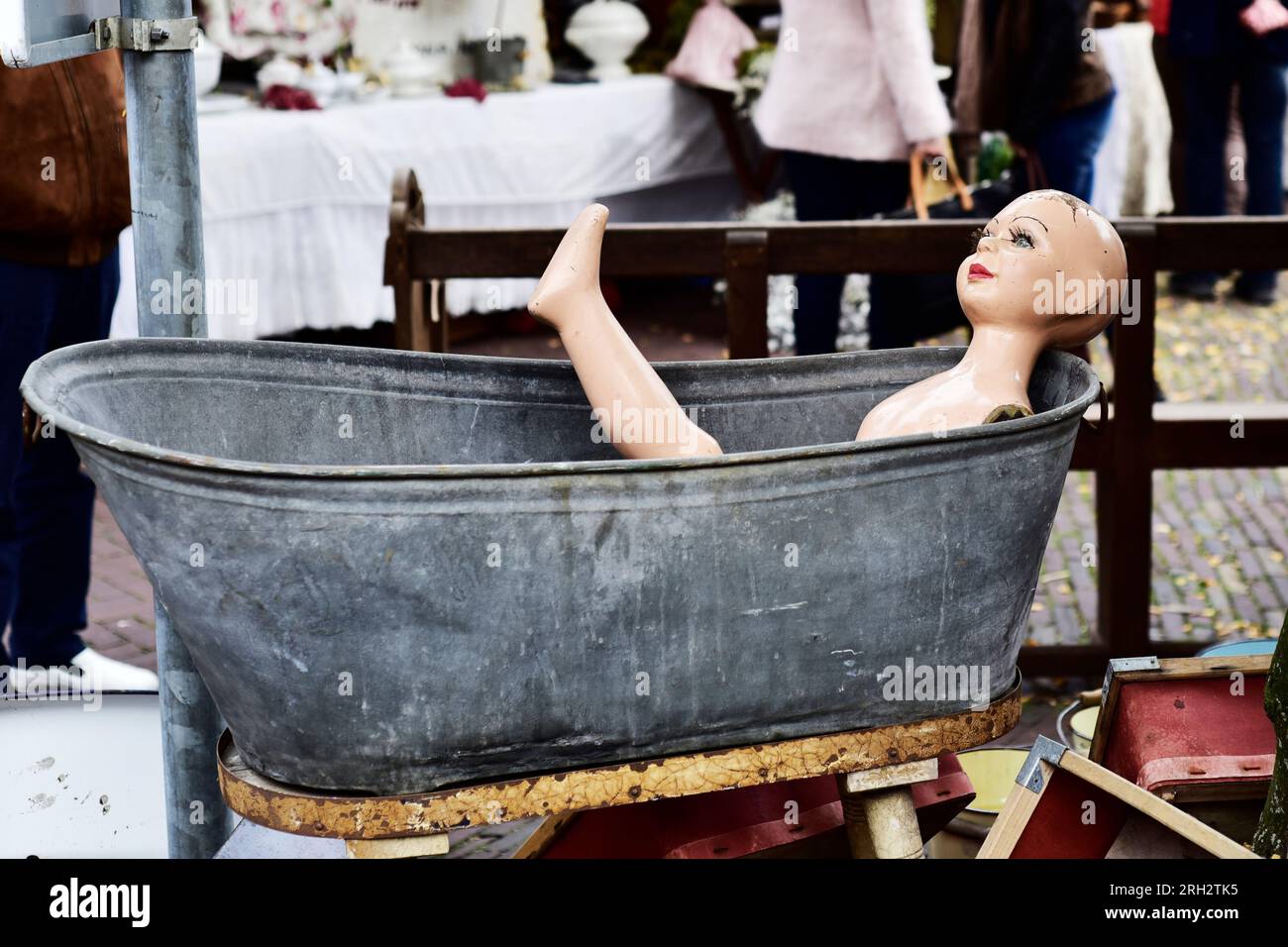 Dans un marché aux puces, une poupée féminine se trouve dans une position gracieuse dans une baignoire en zinc. Les deux sont à vendre Banque D'Images