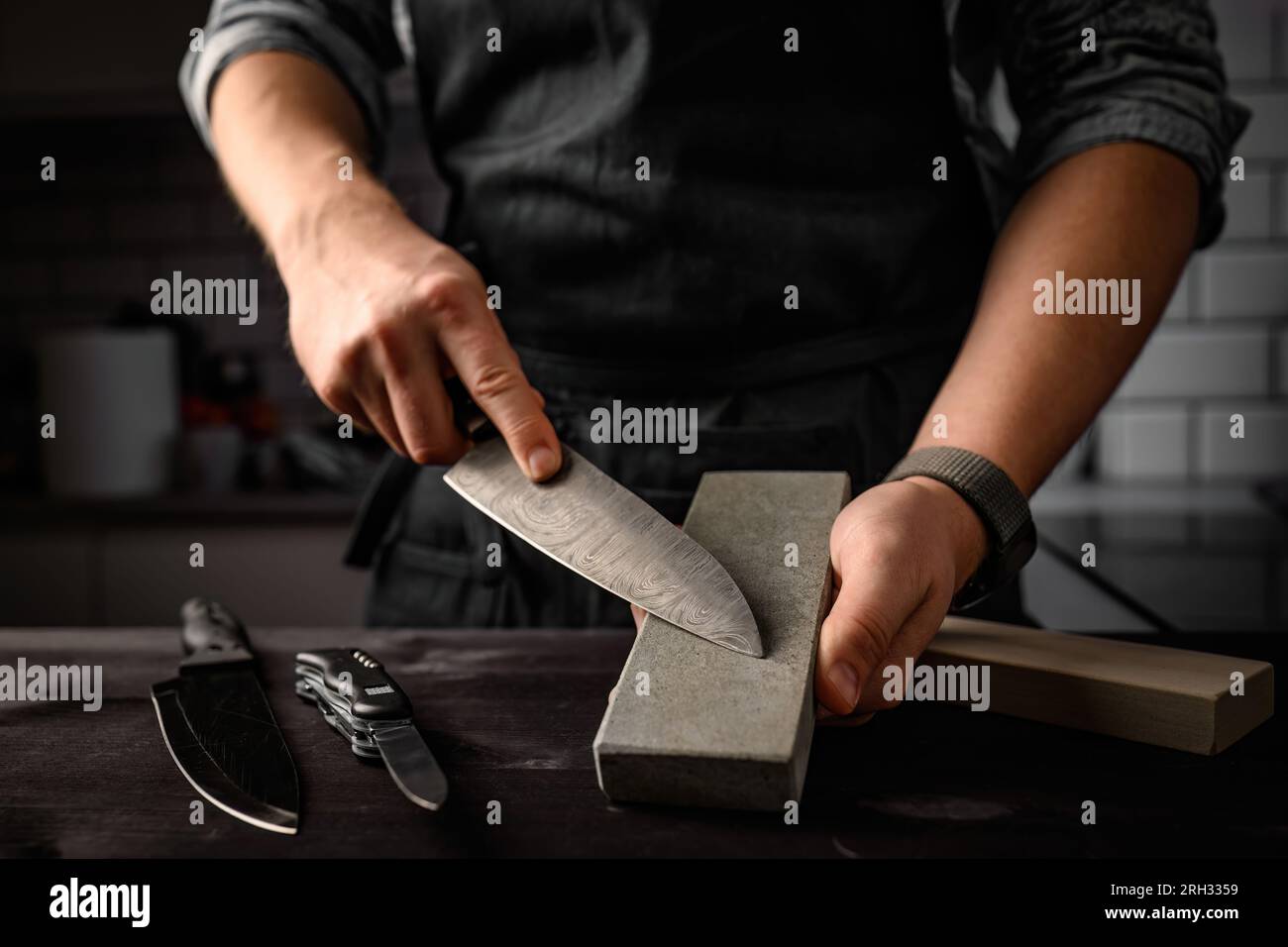 Homme affûtant un couteau avec un outil de pierre d'affûtage. Couteau  principal d'affûtage sur une pierre à affûter Photo Stock - Alamy