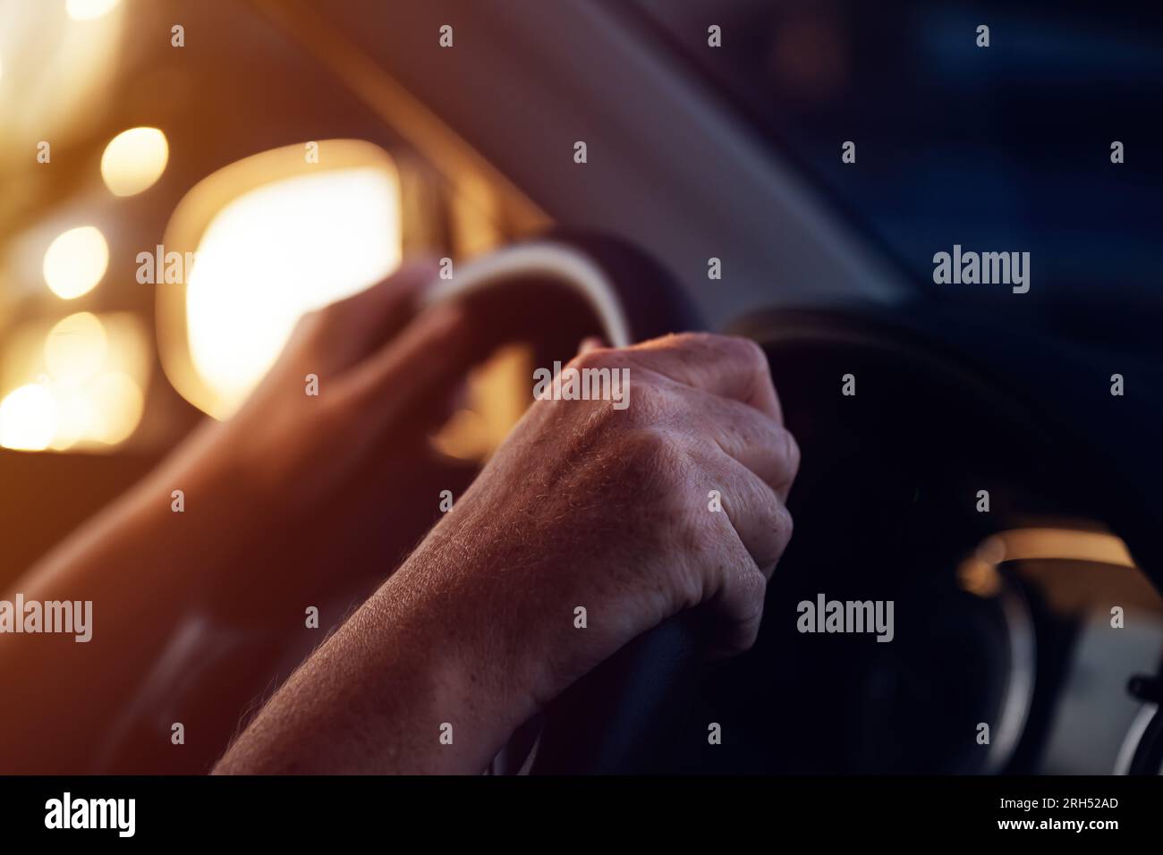 Conducteur féminin tenant fermement le volant de la voiture tout en conduisant son véhicule au coucher du soleil, mise au point sélective Banque D'Images