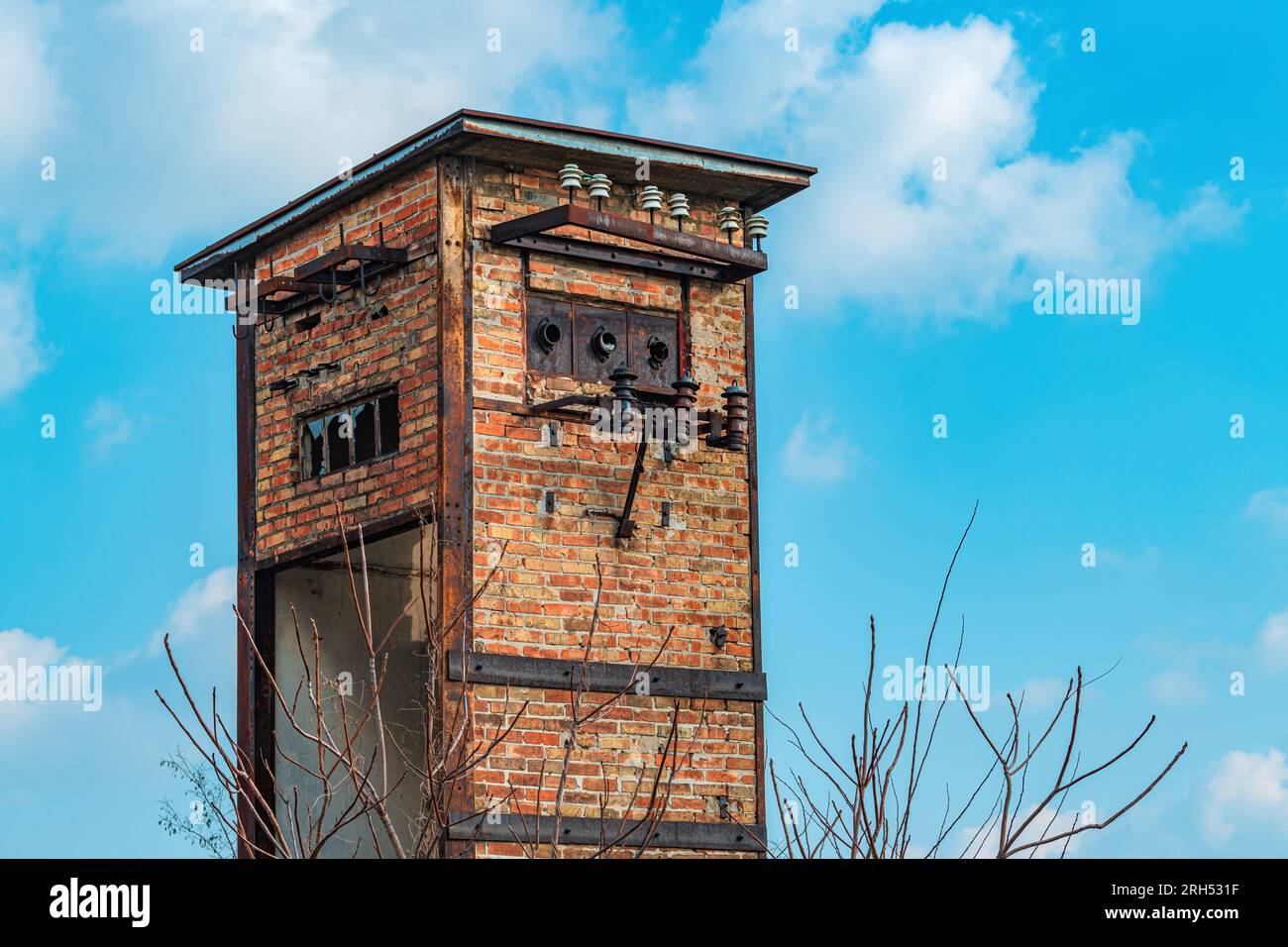 Vieille tour de transformateur de cabine électrique abandonnée usée en briques, contre ciel bleu Banque D'Images