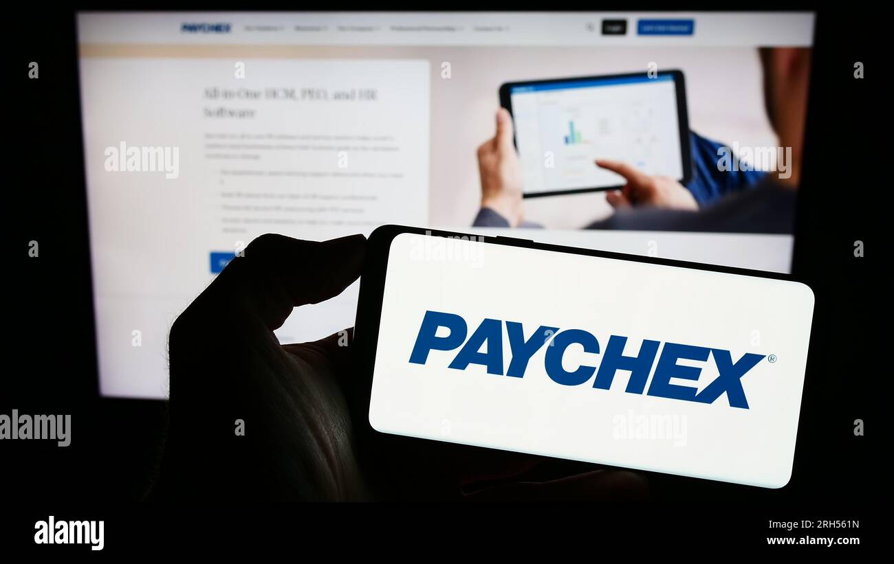 Personne détenant le smartphone avec le logo de la société d'externalisation américaine Paychex Inc. Sur l'écran devant le site Web. Concentrez-vous sur l'affichage du téléphone. Banque D'Images