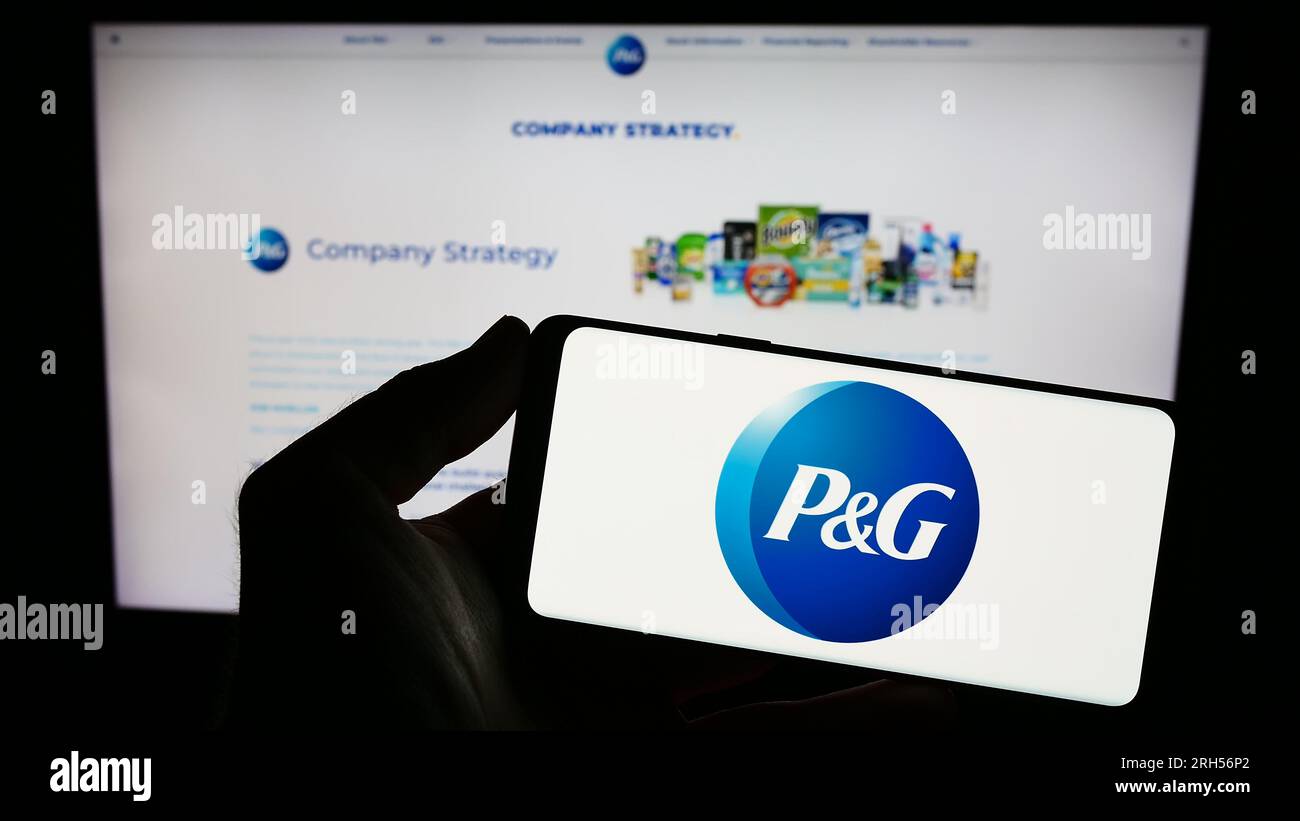 Personne tenant smartphone avec le logo de l'entreprise américaine The Procter Gamble Company sur l'écran en face du site Web. Concentrez-vous sur l'affichage du téléphone. Banque D'Images