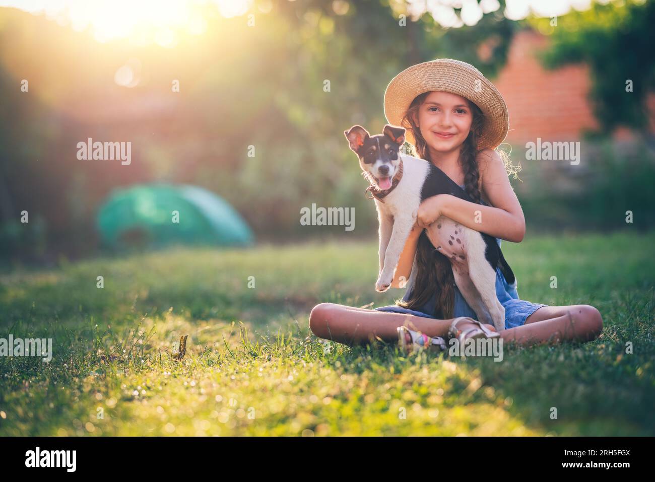 Fille heureuse jouant avec mignon chiot ludique petit chien en plein air sur une journée ensoleillée dans un parc Banque D'Images