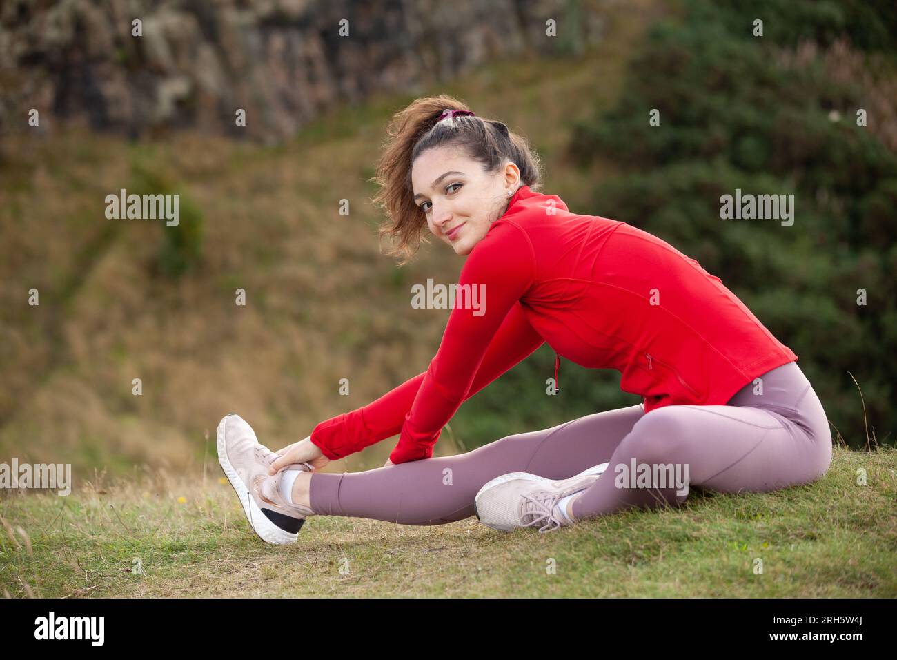 Une jeune femme portant des leggings qui s'étirent dans un parc public d'Édimbourg Banque D'Images