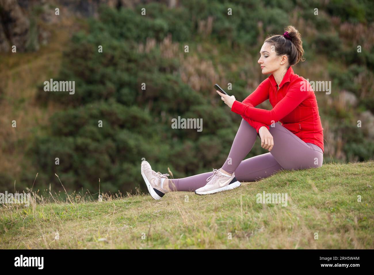 Jeune femme vérifiant son téléphone tout en faisant de l'exercice Banque D'Images