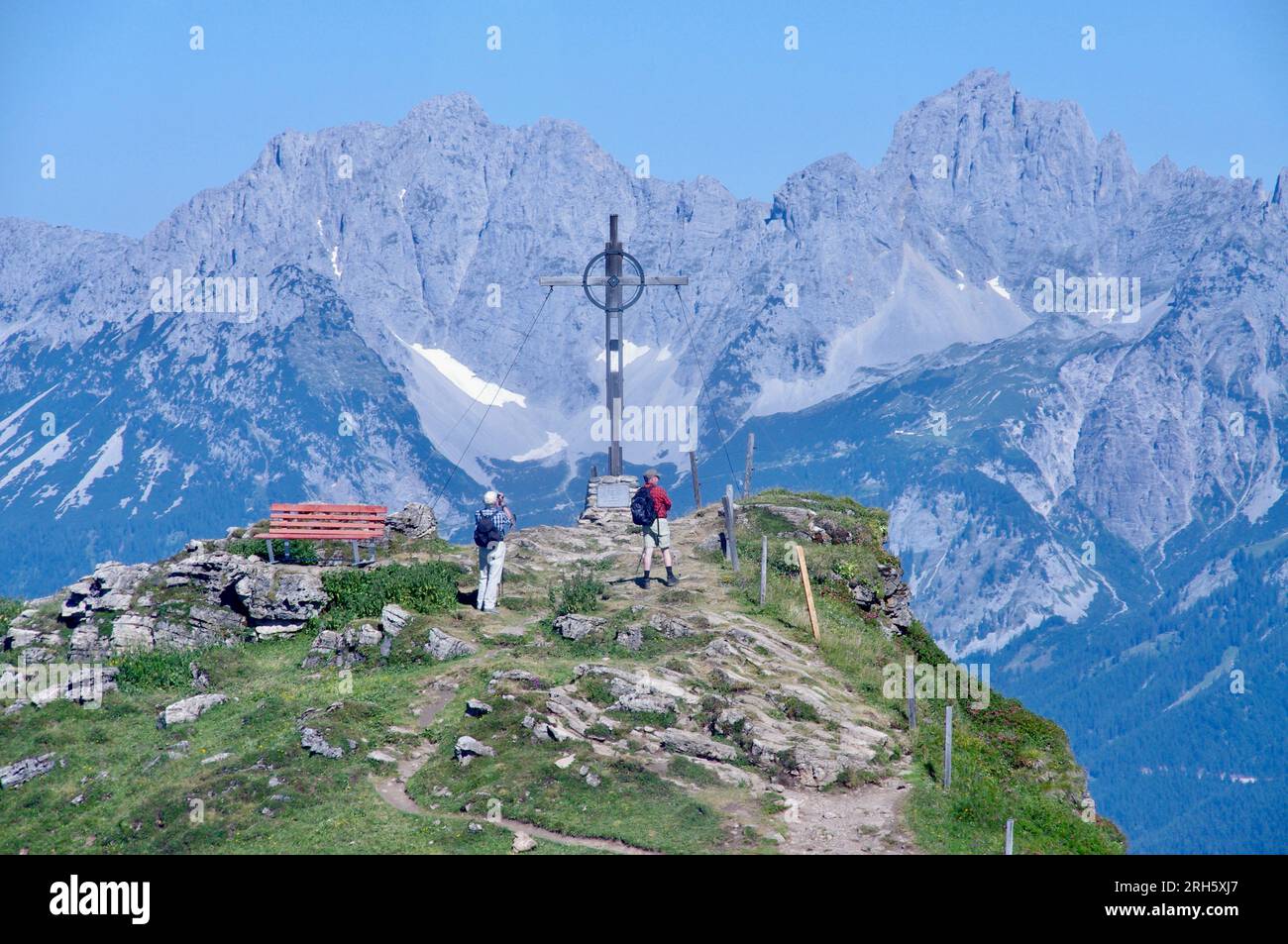 Kitzbuhel, Autriche, la croix du sommet à Kitzbuheler Horn avec des montagnes derrière. Banque D'Images