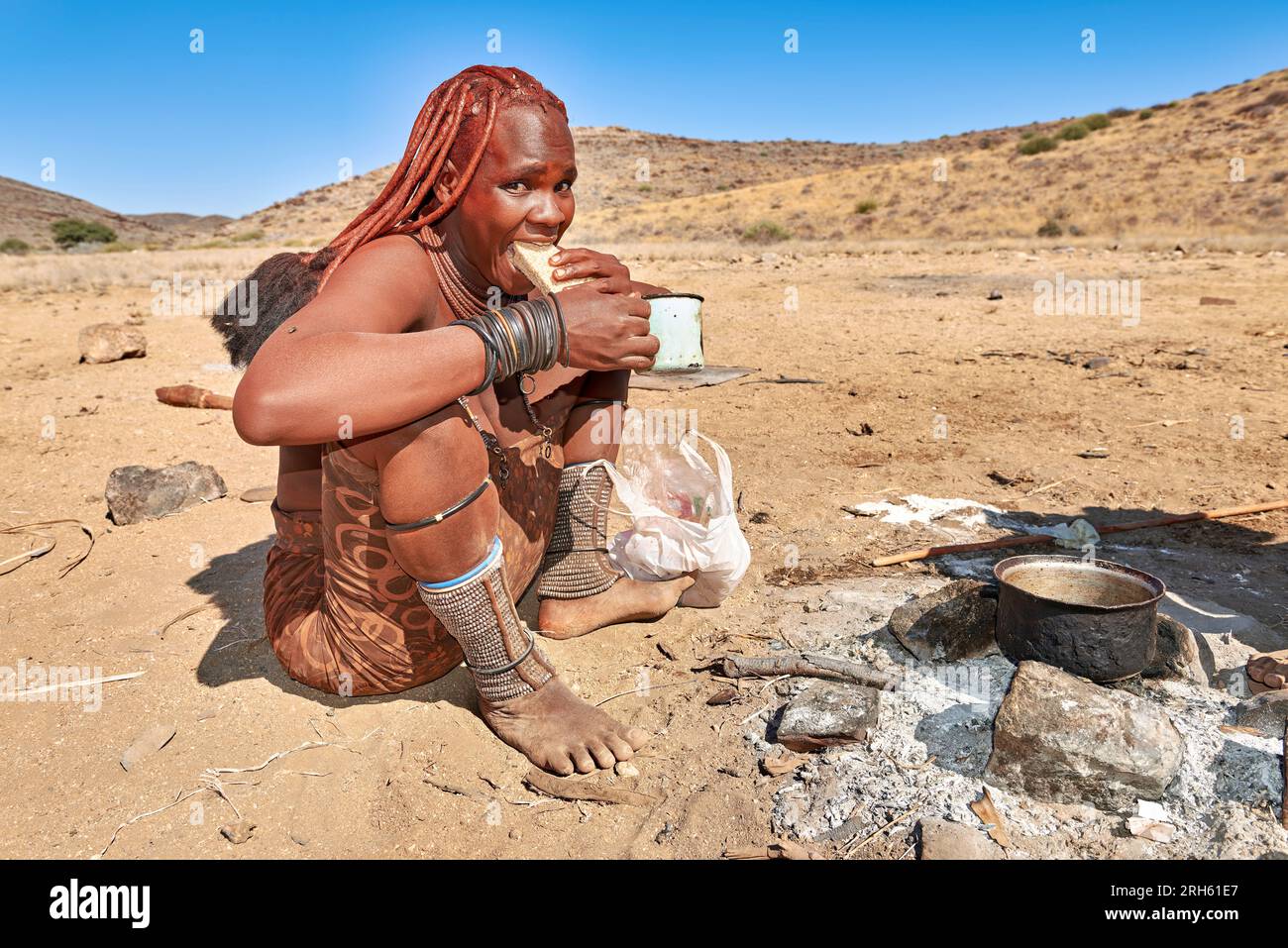 Namibie. Portrait d'une femme Himba mangeant du pain dans la région de Kunene Banque D'Images